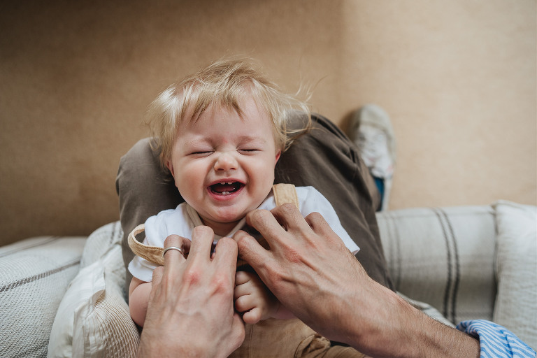 Best Devon family photography: a young boy laughing as his father tickles him