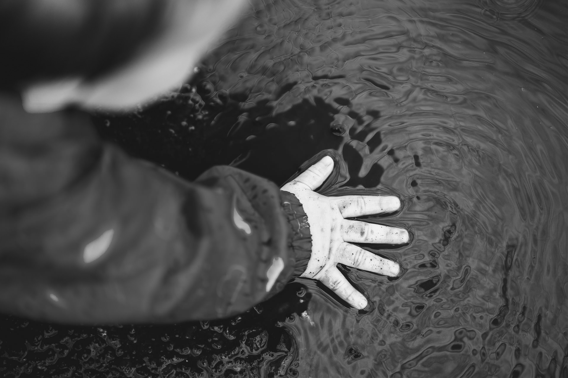 A baby's hand in a muddy puddle