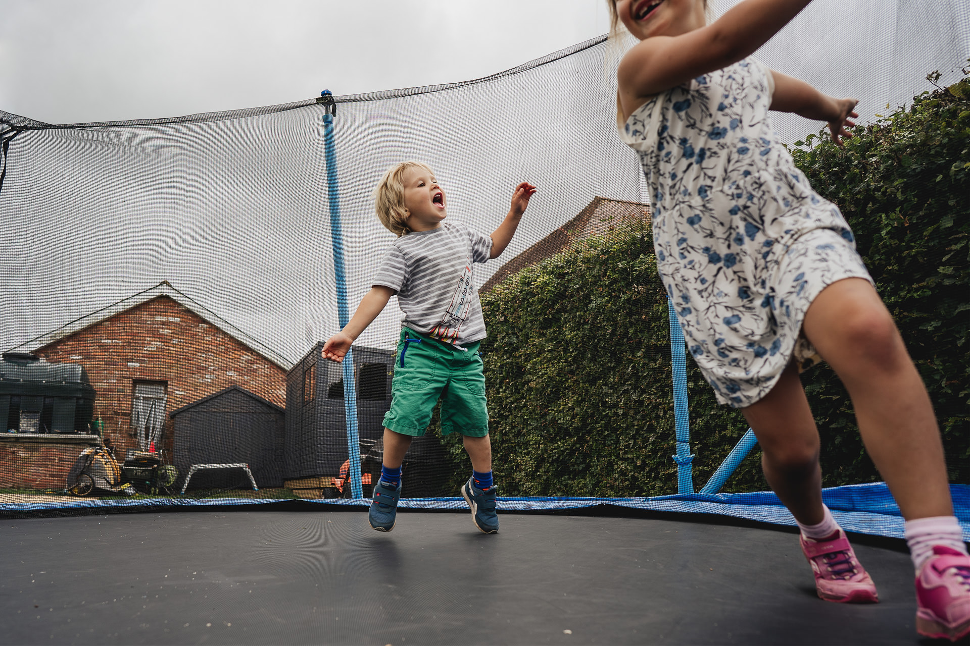 Two siblings playing on a trampoline