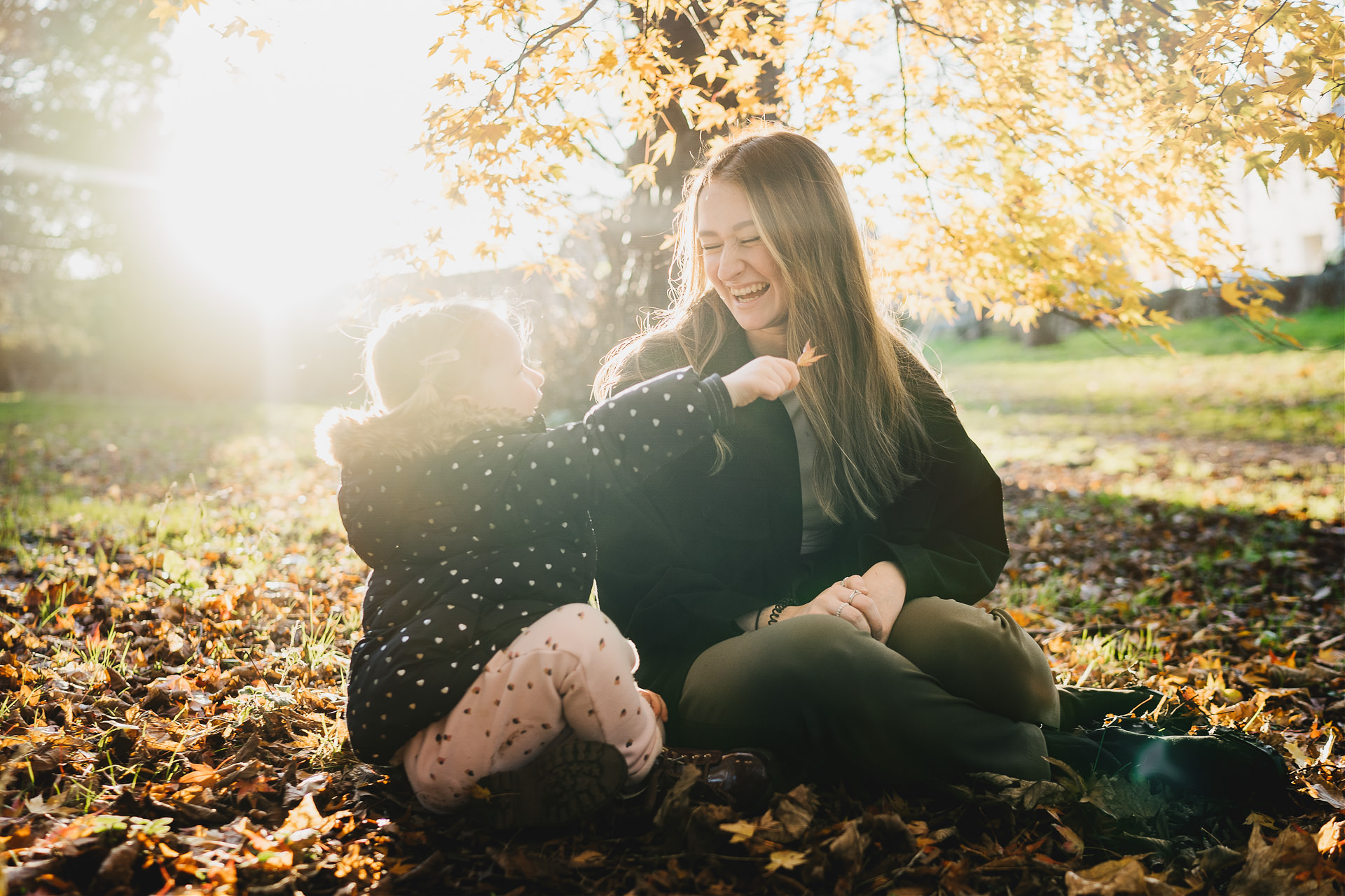 Two sisters laughing together in autumn sunlight