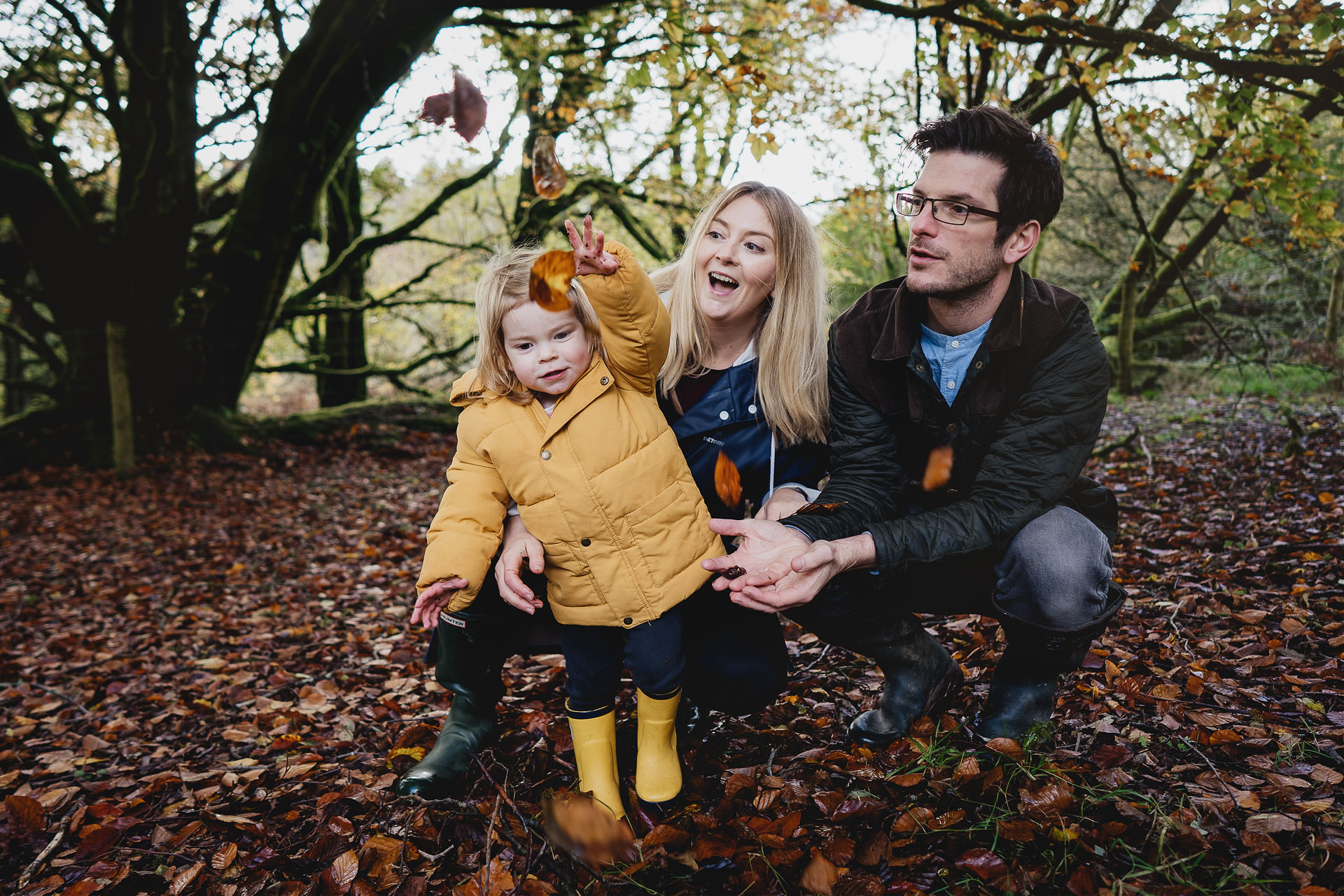 Photograph of a young family playing in autumn leaves