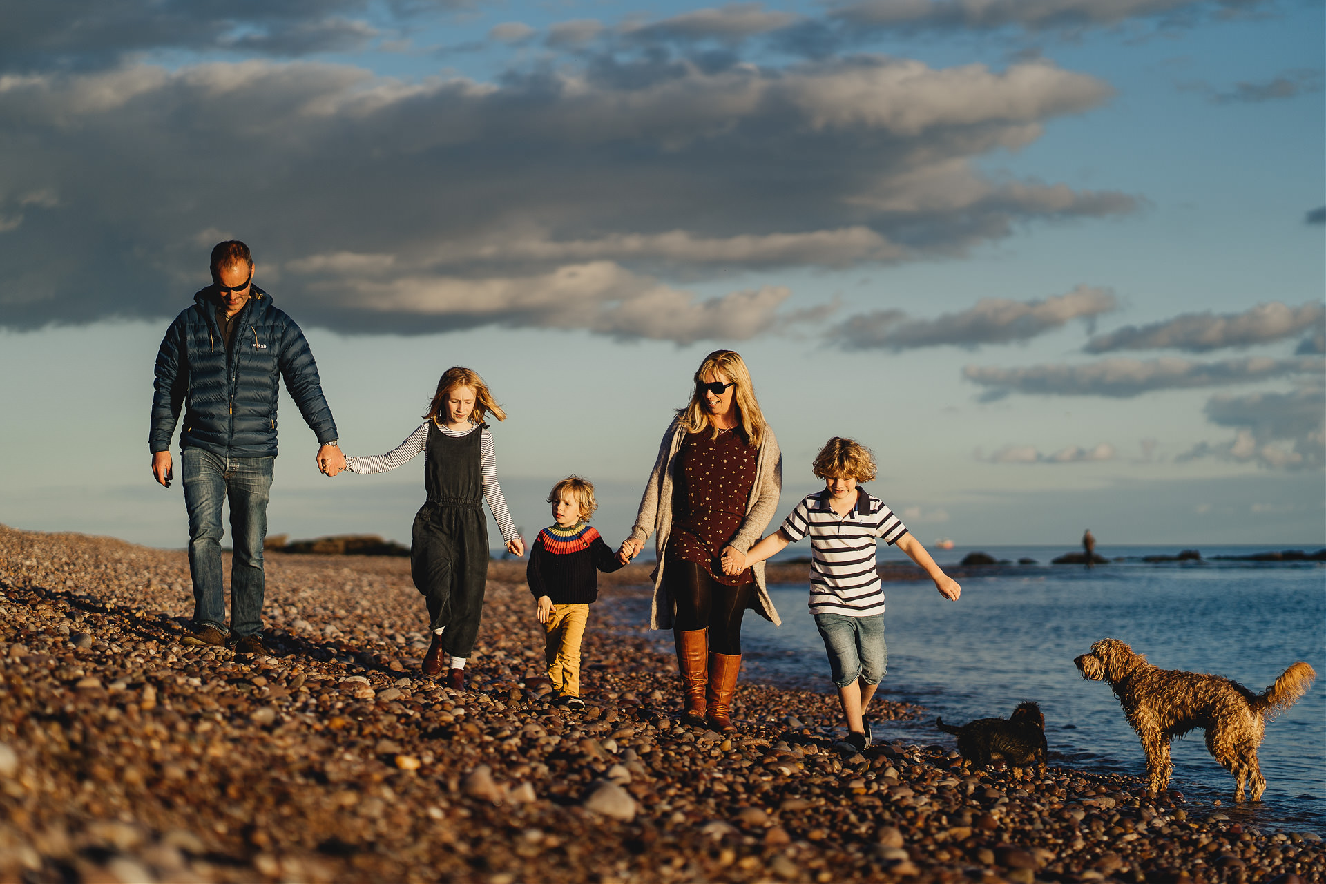 Devon family photography at the beach, with a family with two dogs walking on the beach together