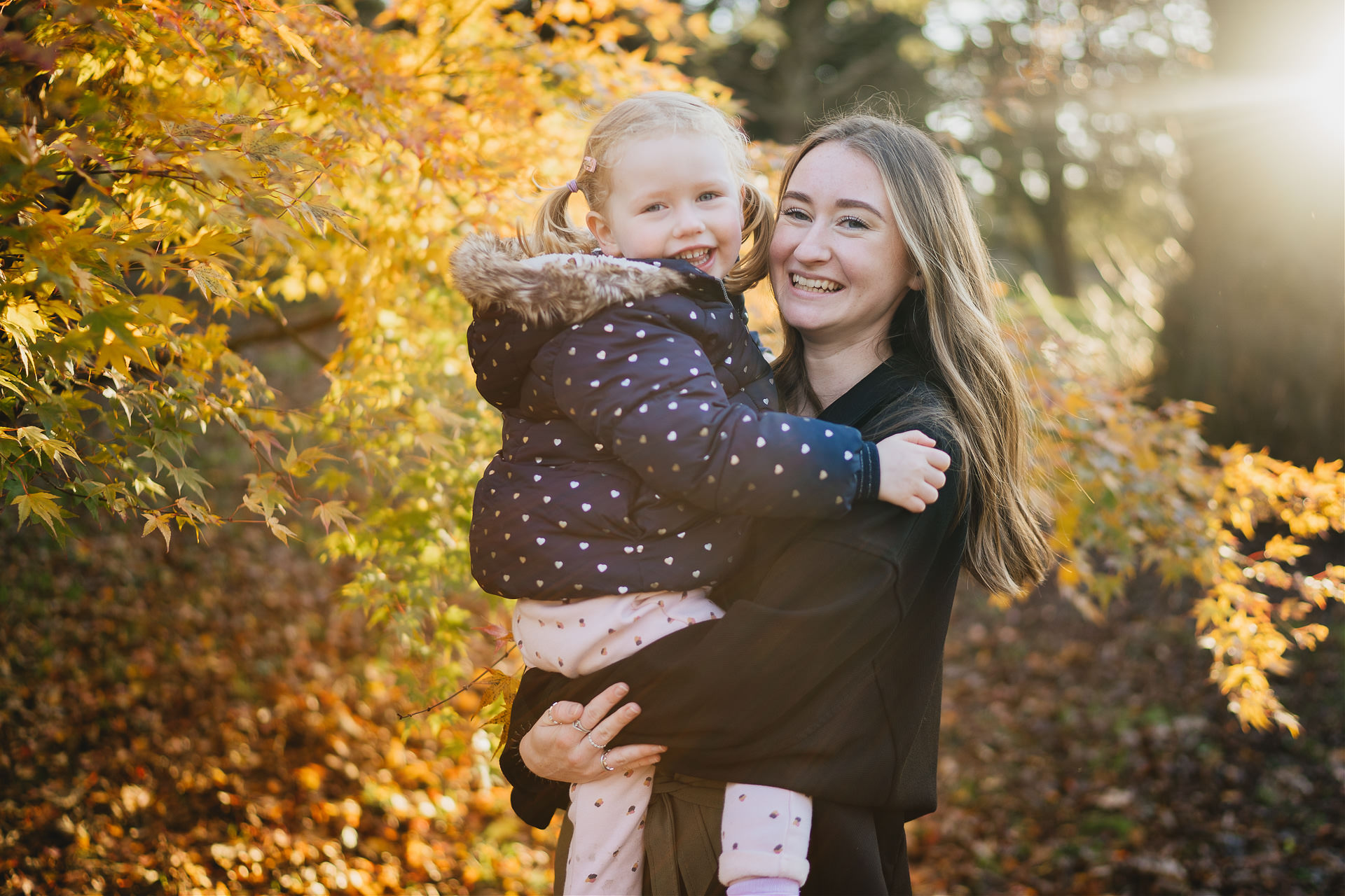 Exeter family photography of two sisters smiling together by autumn leaves