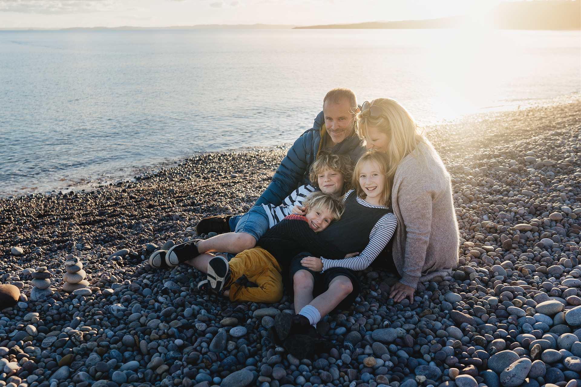 Best Devon family photography portrait of a family with three children sitting together by the sea
