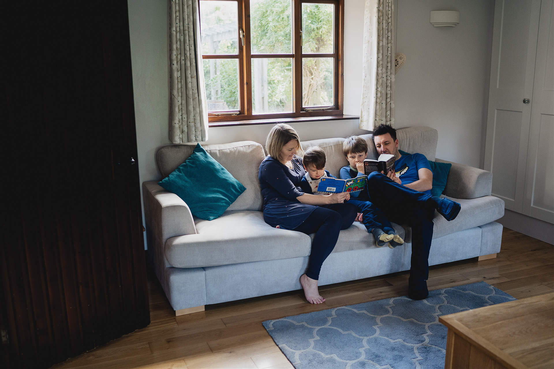 Relaxed family photography image of a family reading at home on the sofa together