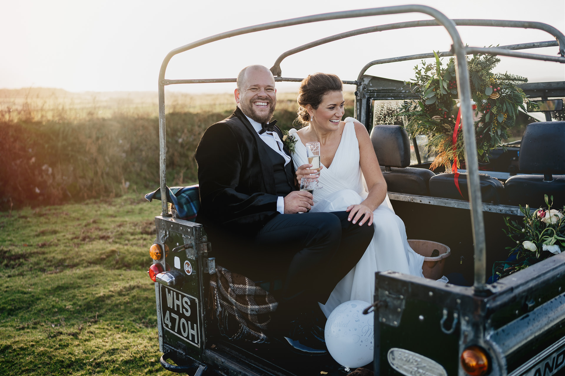 Bride and groom laughing in the back of Landrover