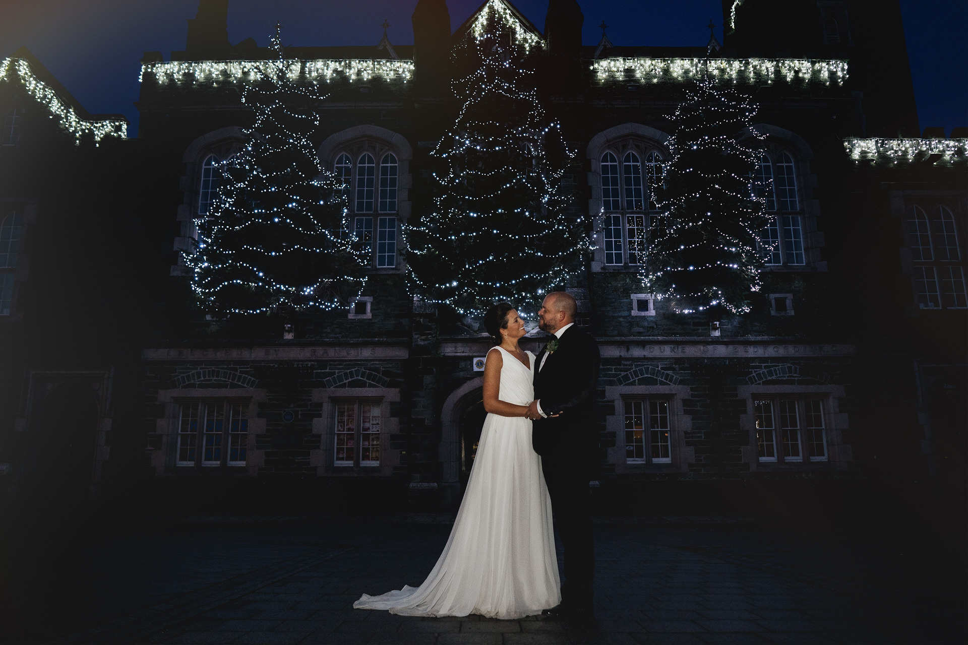 Bride and groom with sparkly Christmas trees behind