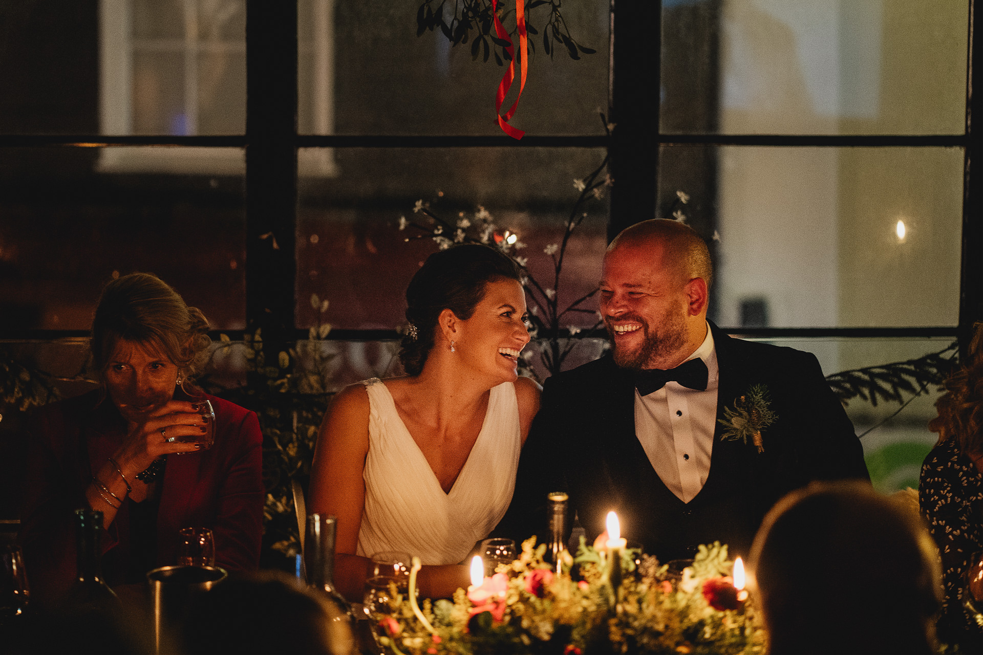 Bride and groom laughing together at a dinner table
