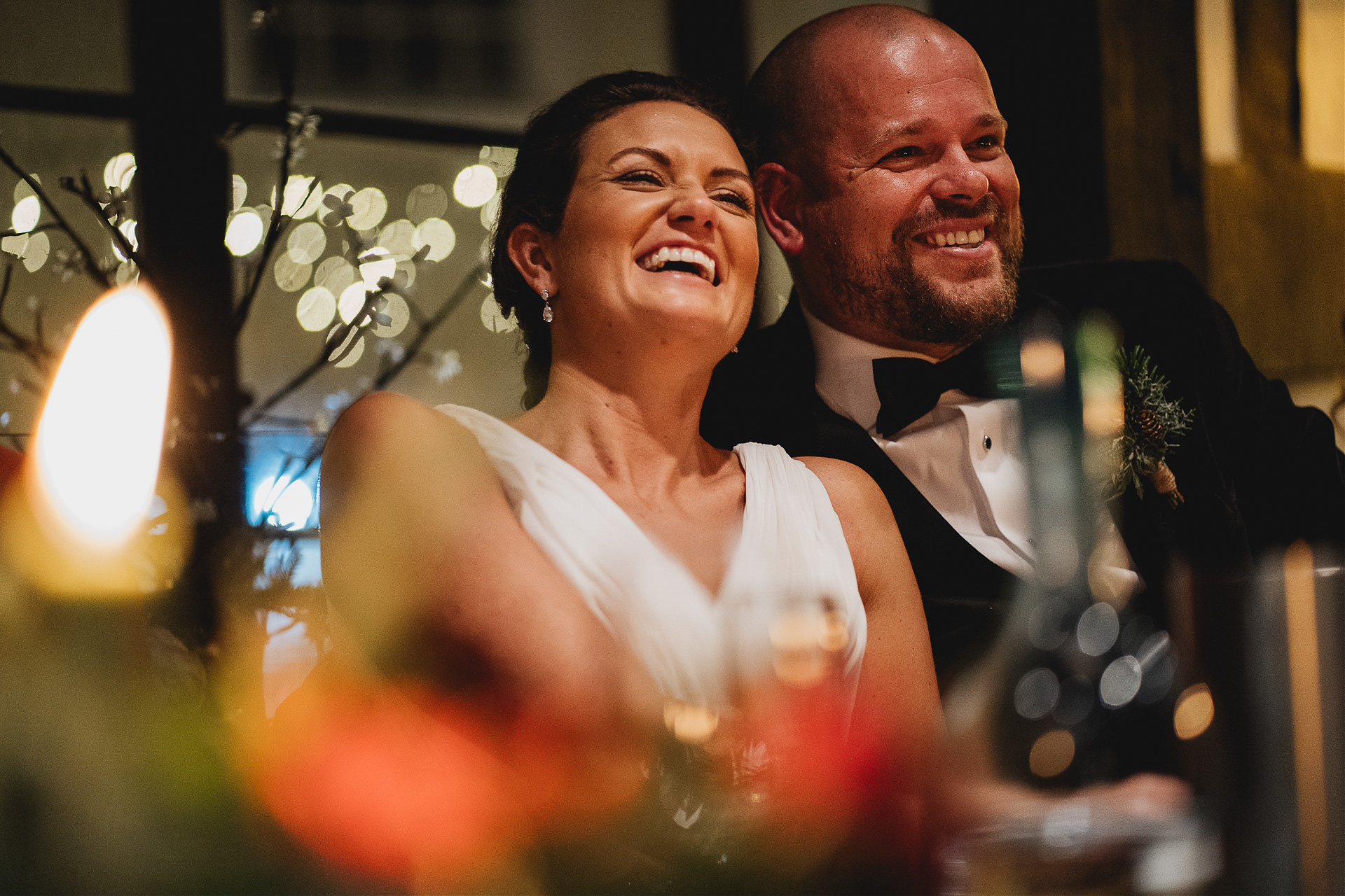 Bride and groom laughing together with Christmas lights