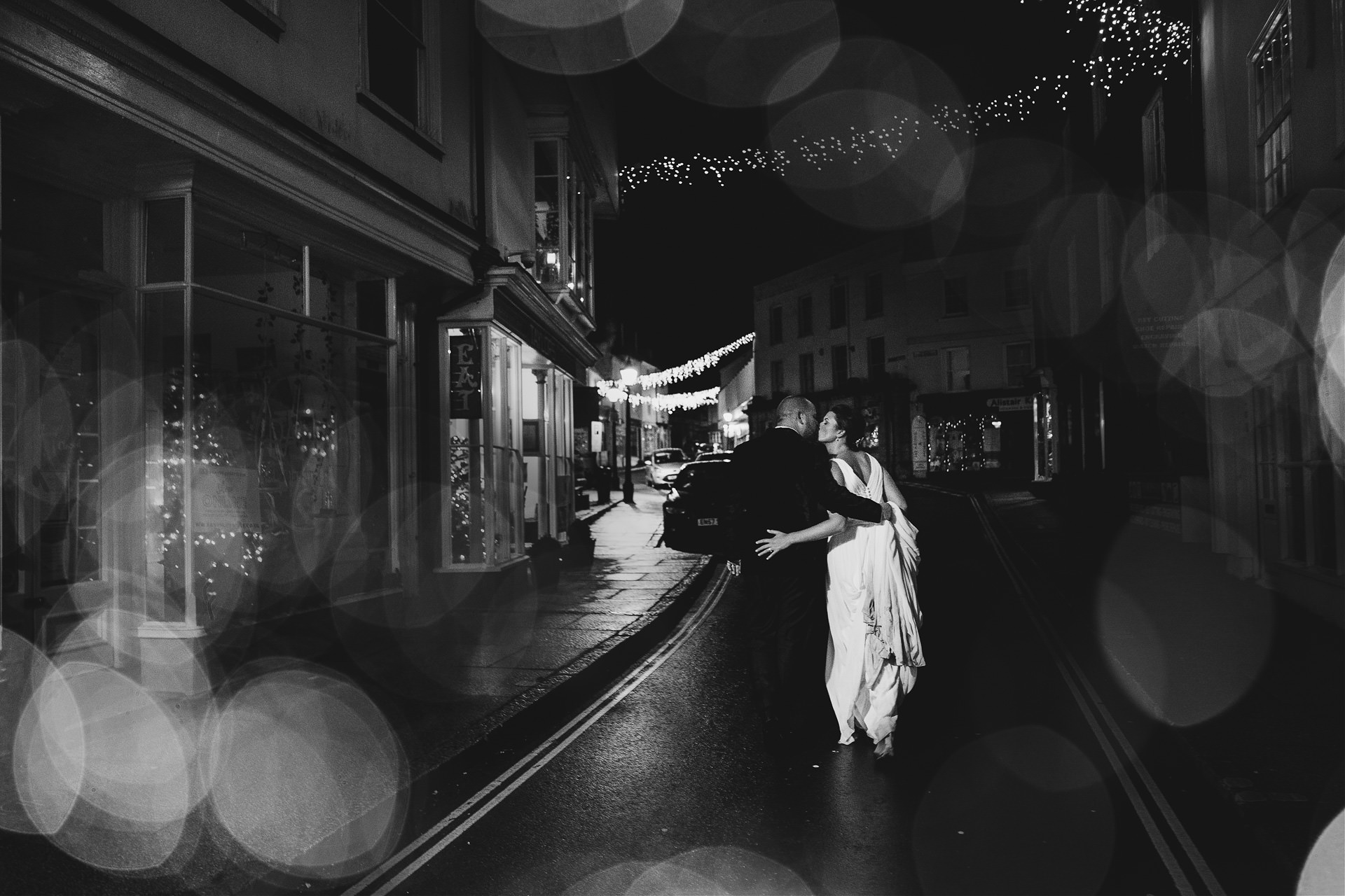 Bride and groom kissing in a Christmassy street