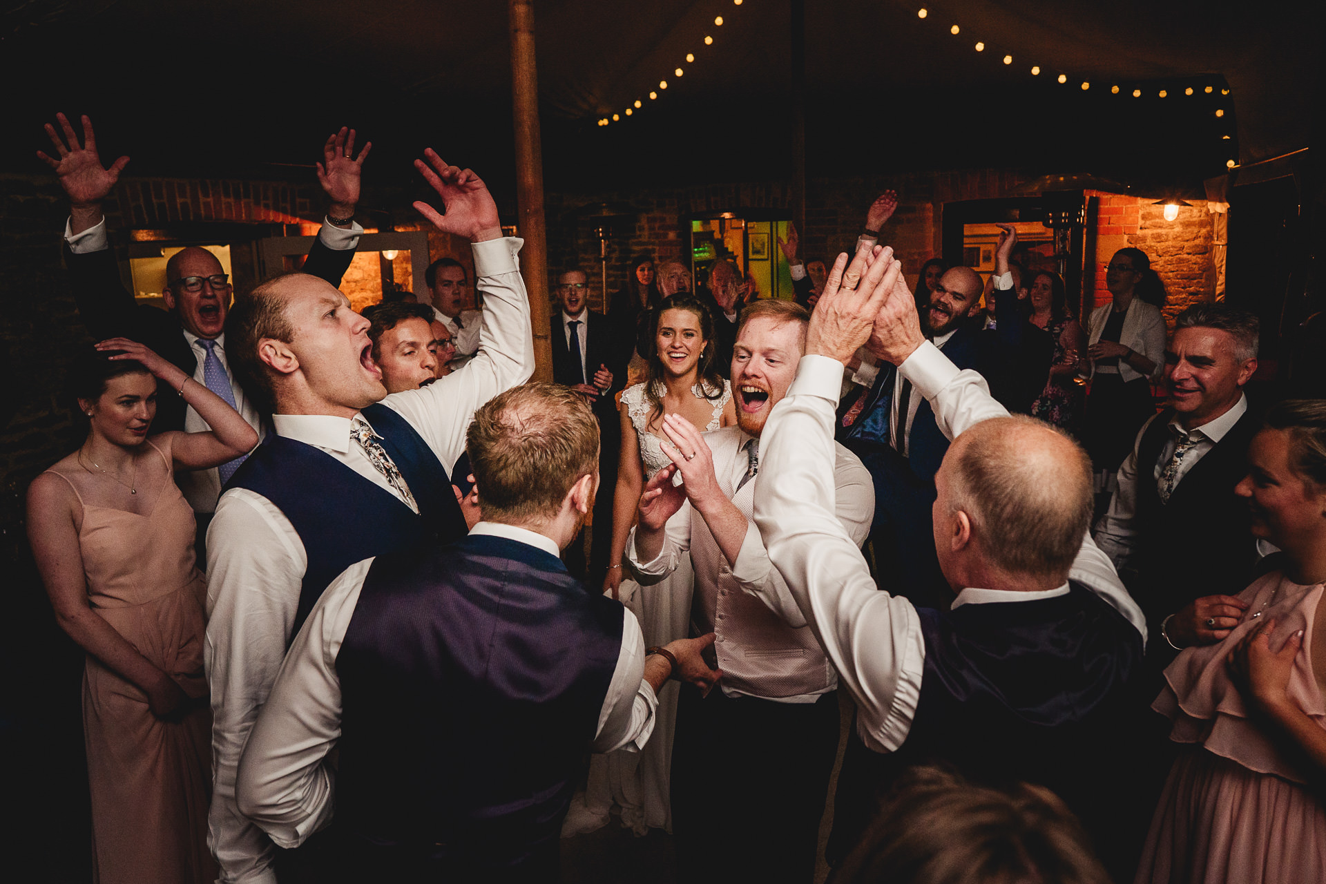 Wedding guests animatedly dancing with hands in the air