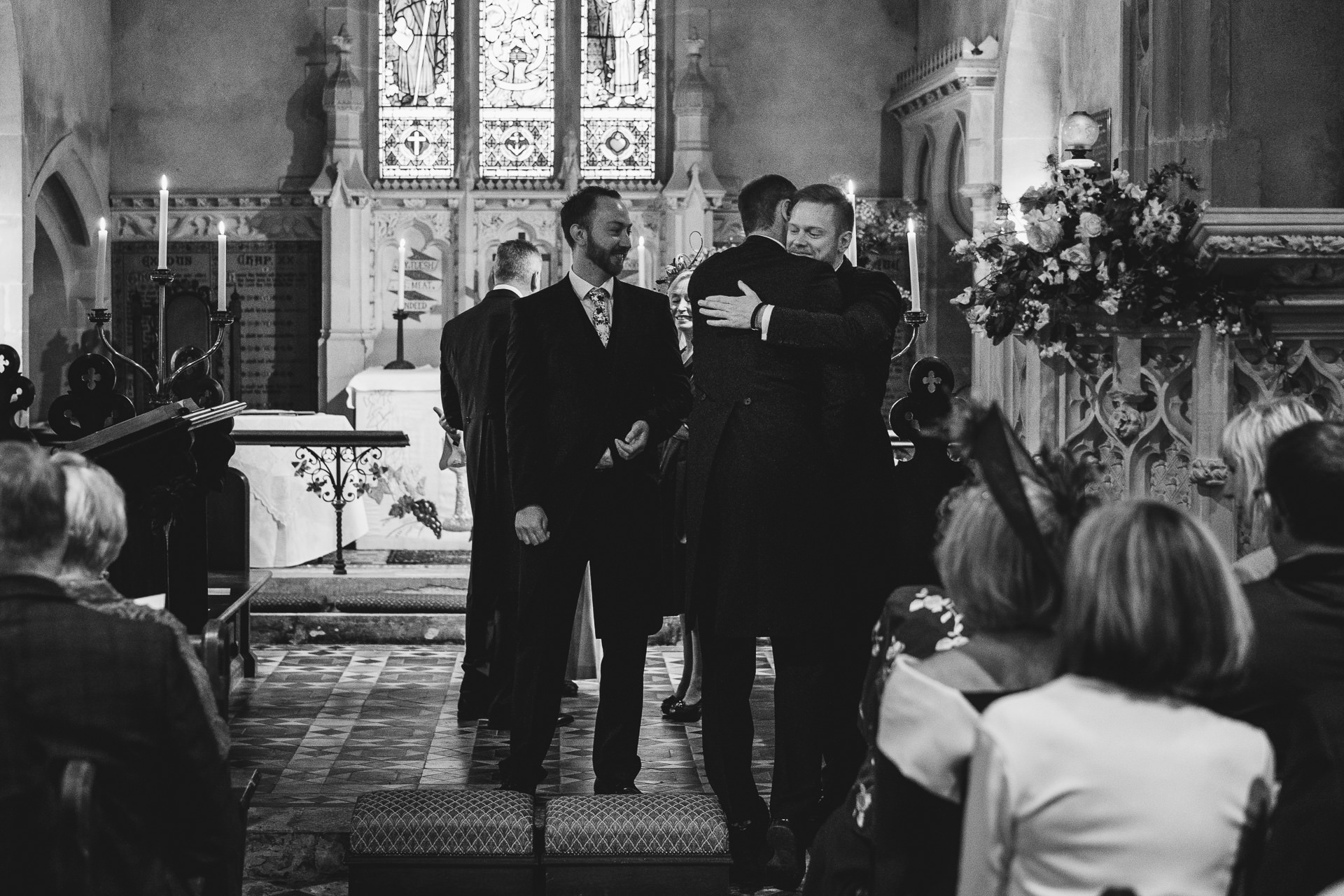Groom hugging usher at the front of a church