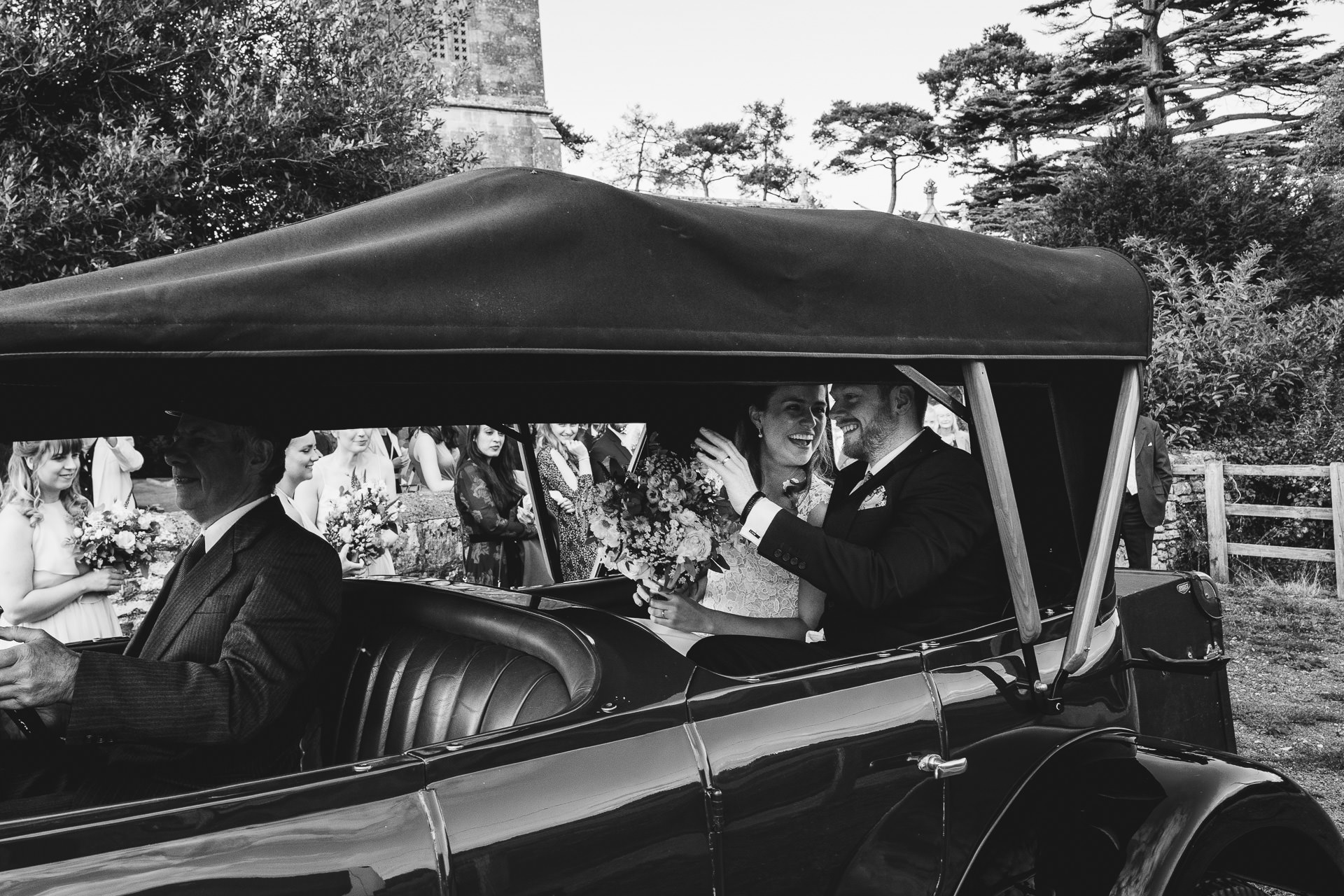 Bride and groom smiling at each other in a wedding car