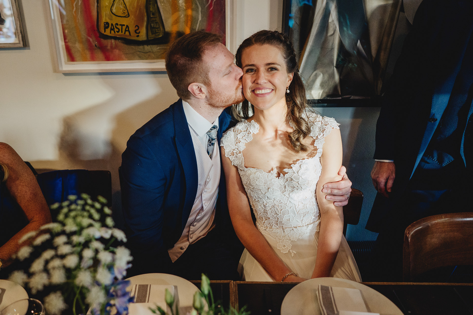 Groom kissing bride while seated at the table
