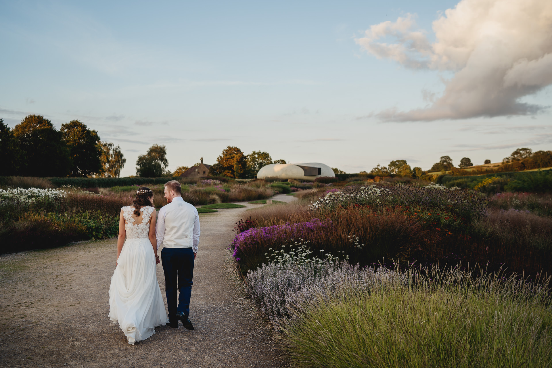 Bride and groom walking hand in hand through gardens at Hauser & Wirth Somerset