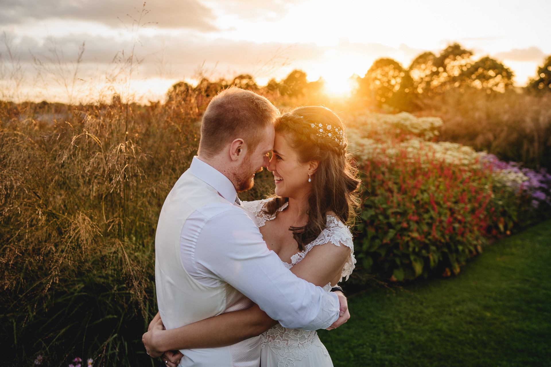Bride and groom cuddling with golden sunset behind at Hauser & Wirth somerset