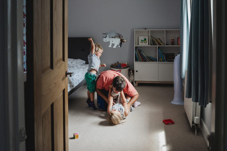 Family photography at home, a father and children playing in a bedroom
