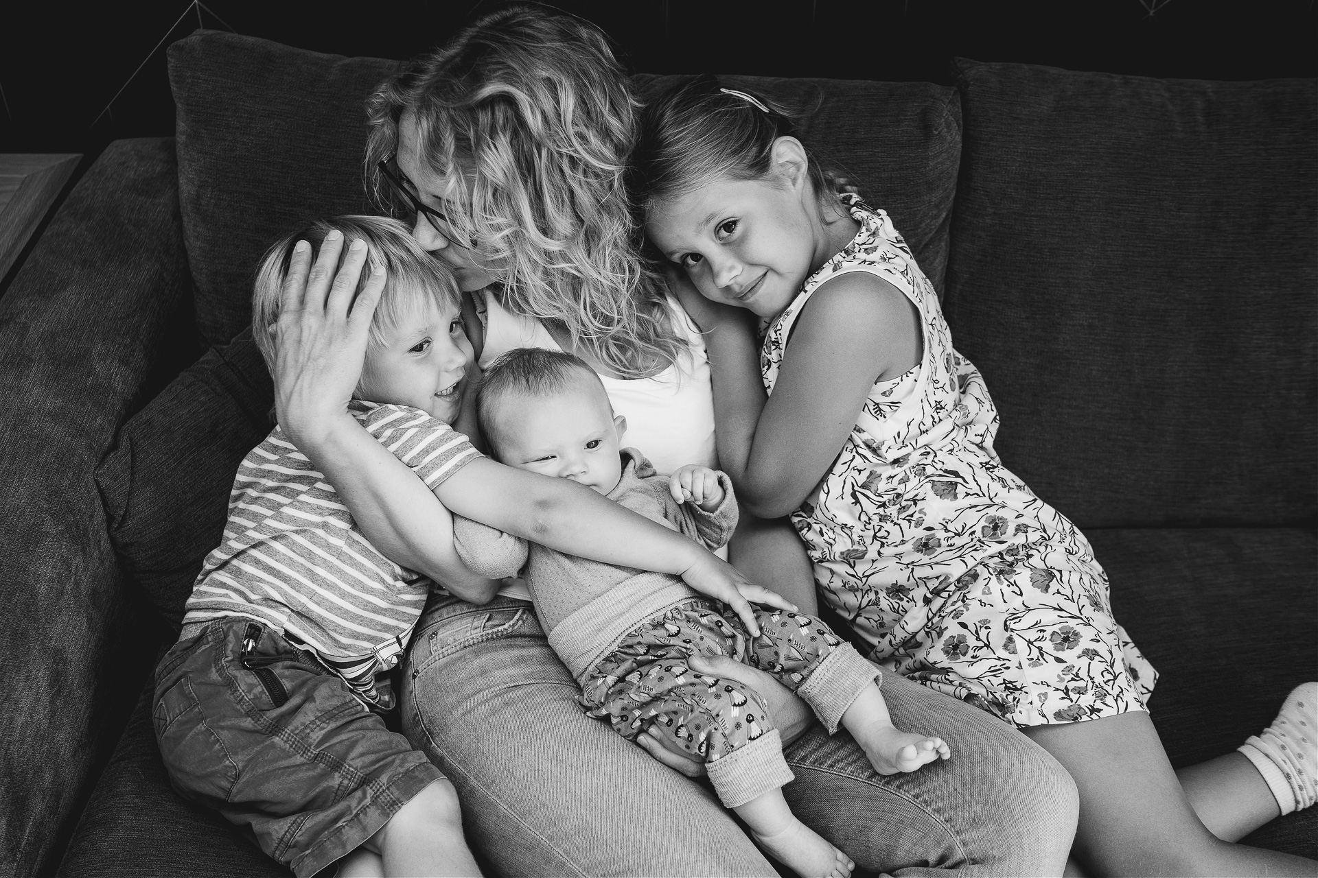 Photograph of a mother and three children on a sofa at home