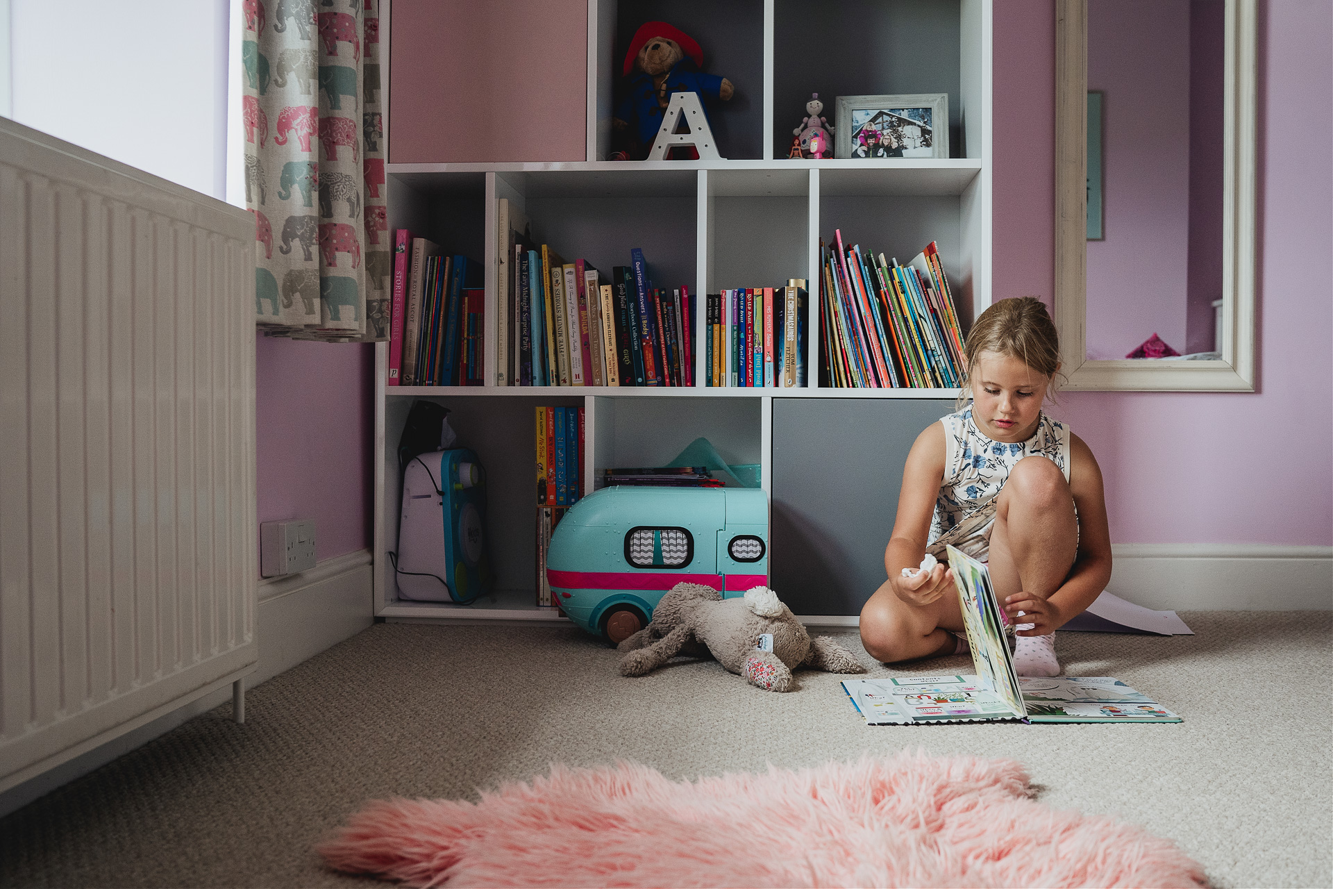 A young girl reading books in her bedroom