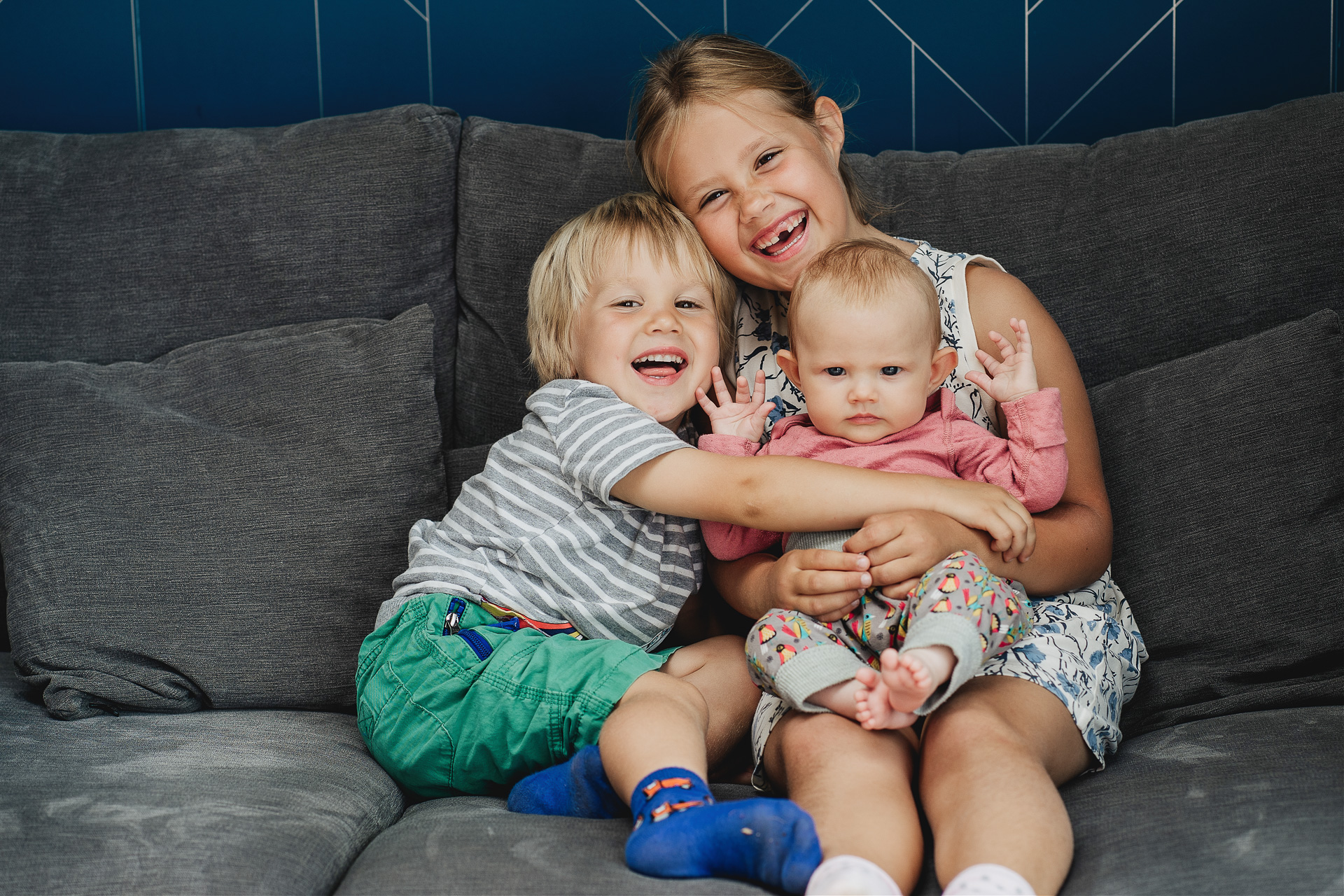 Family photography at home, three children on a sofa together