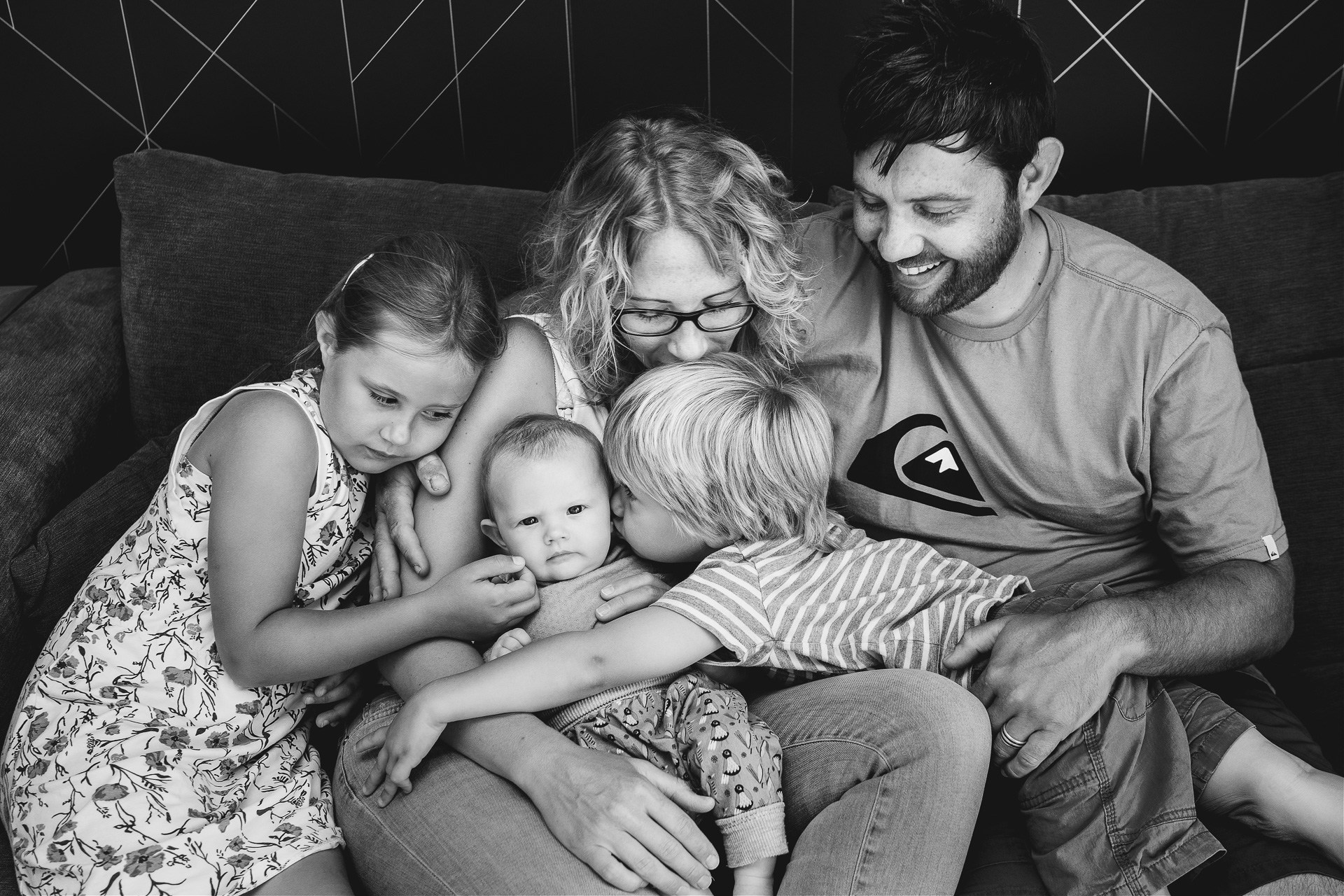Family photography at home, all sitting on the sofa cuddling together