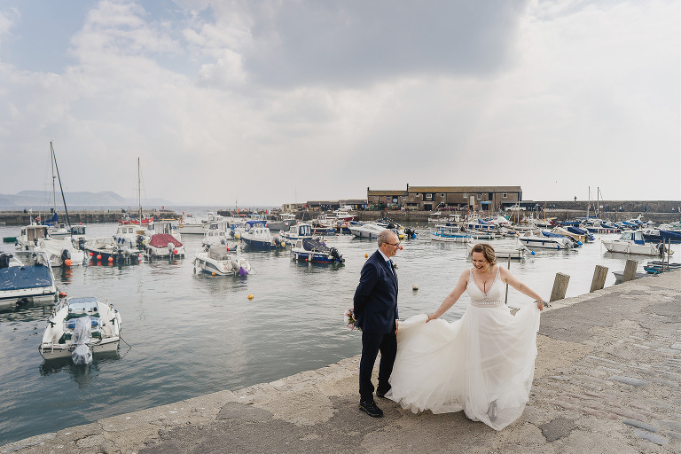 Elopement wedding by the sea, bride and groom laughing together in Lyme Regis harbour