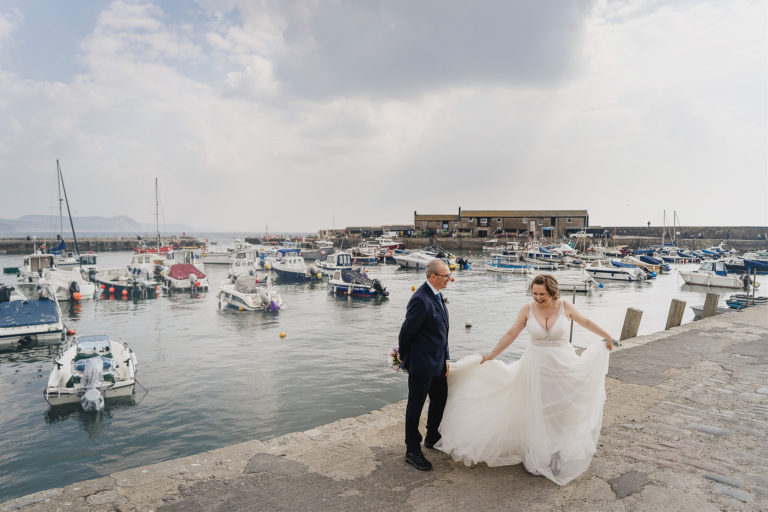 Elopement wedding by the sea, bride and groom laughing together in Lyme Regis harbour