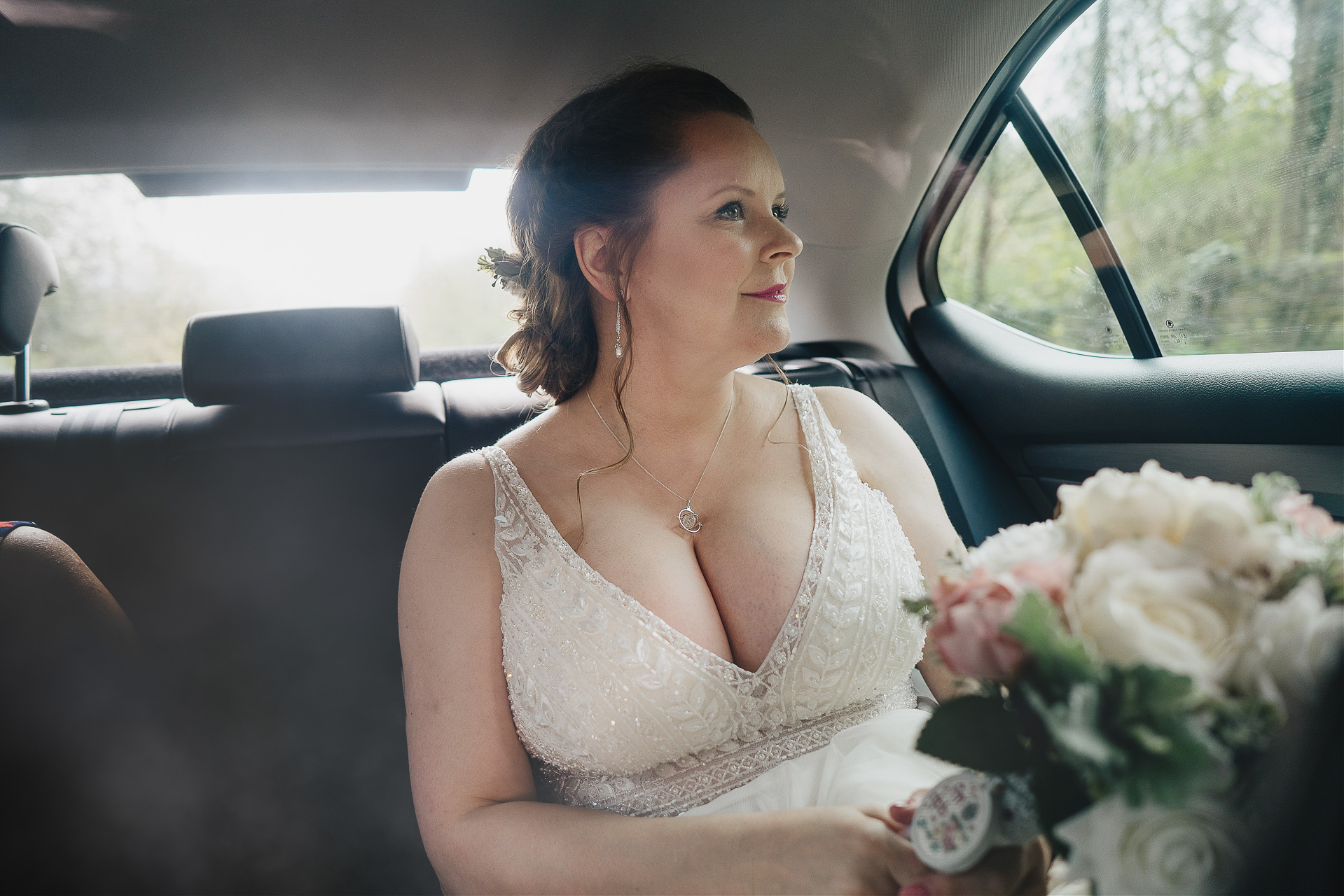 Bride with flowers in a car driving to wedding ceremony