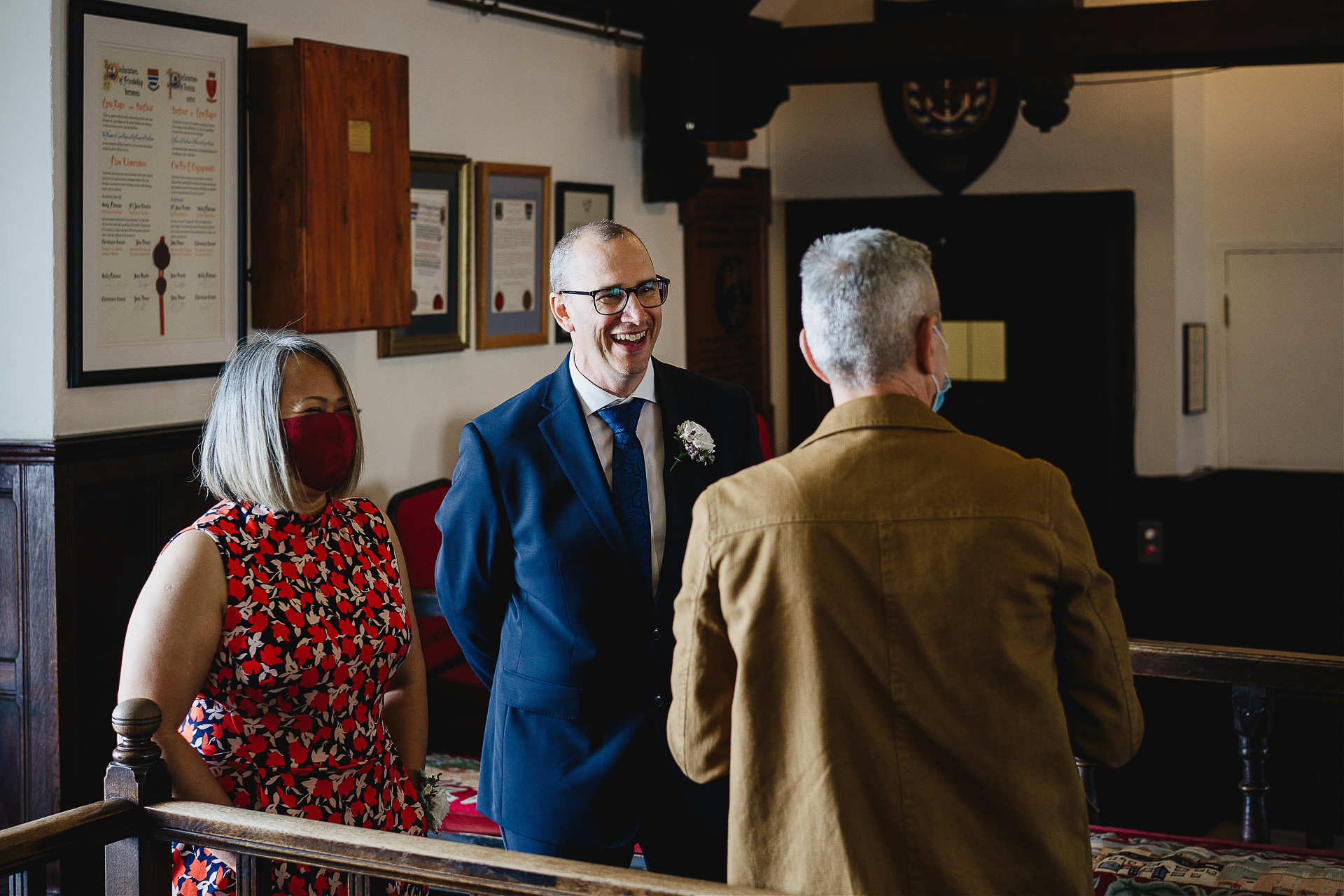 Groom laughing with wedding guests inside Lyme Regis Guildhall