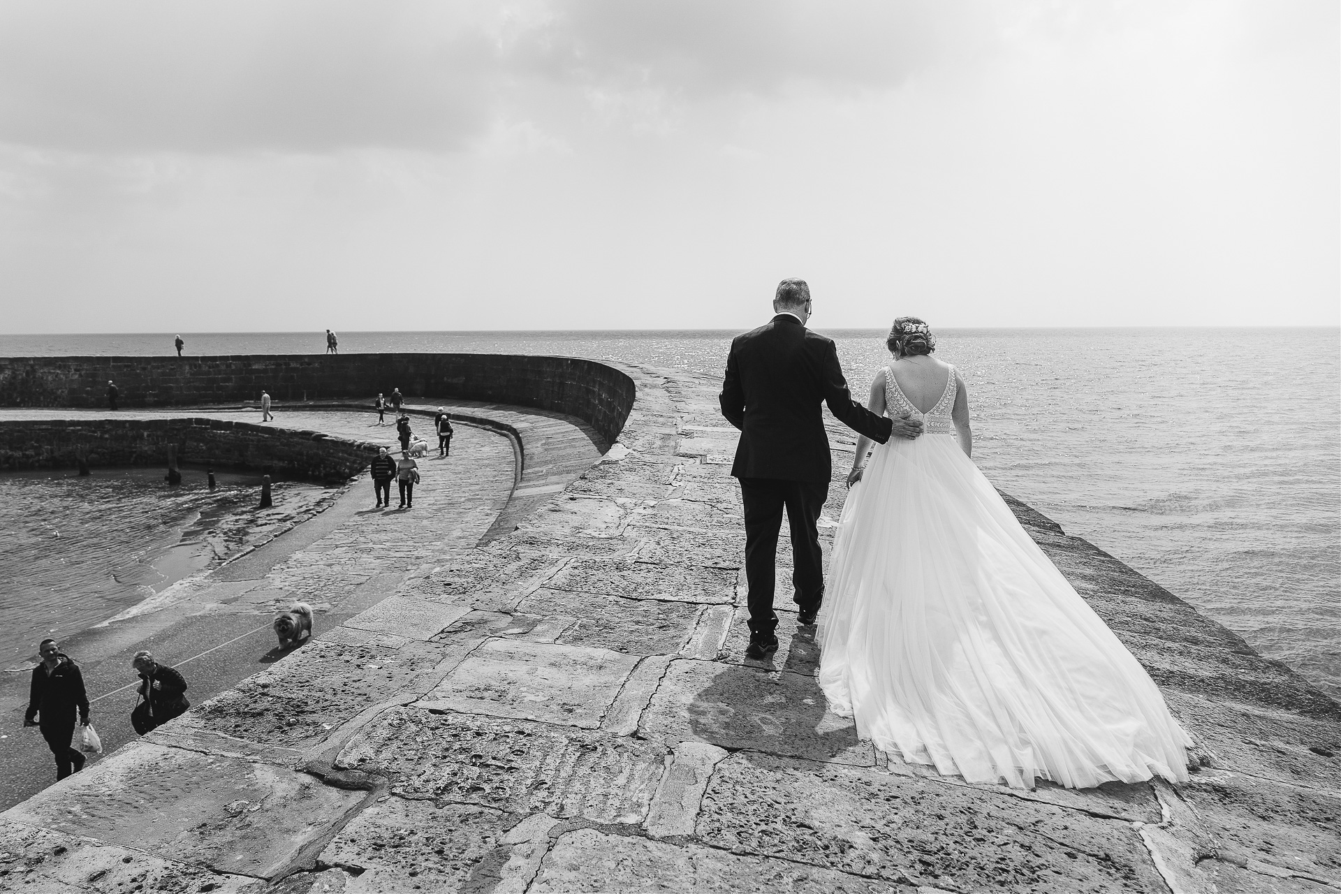 Bride and groom walking along the Cobb by the sea in Lyme Regis