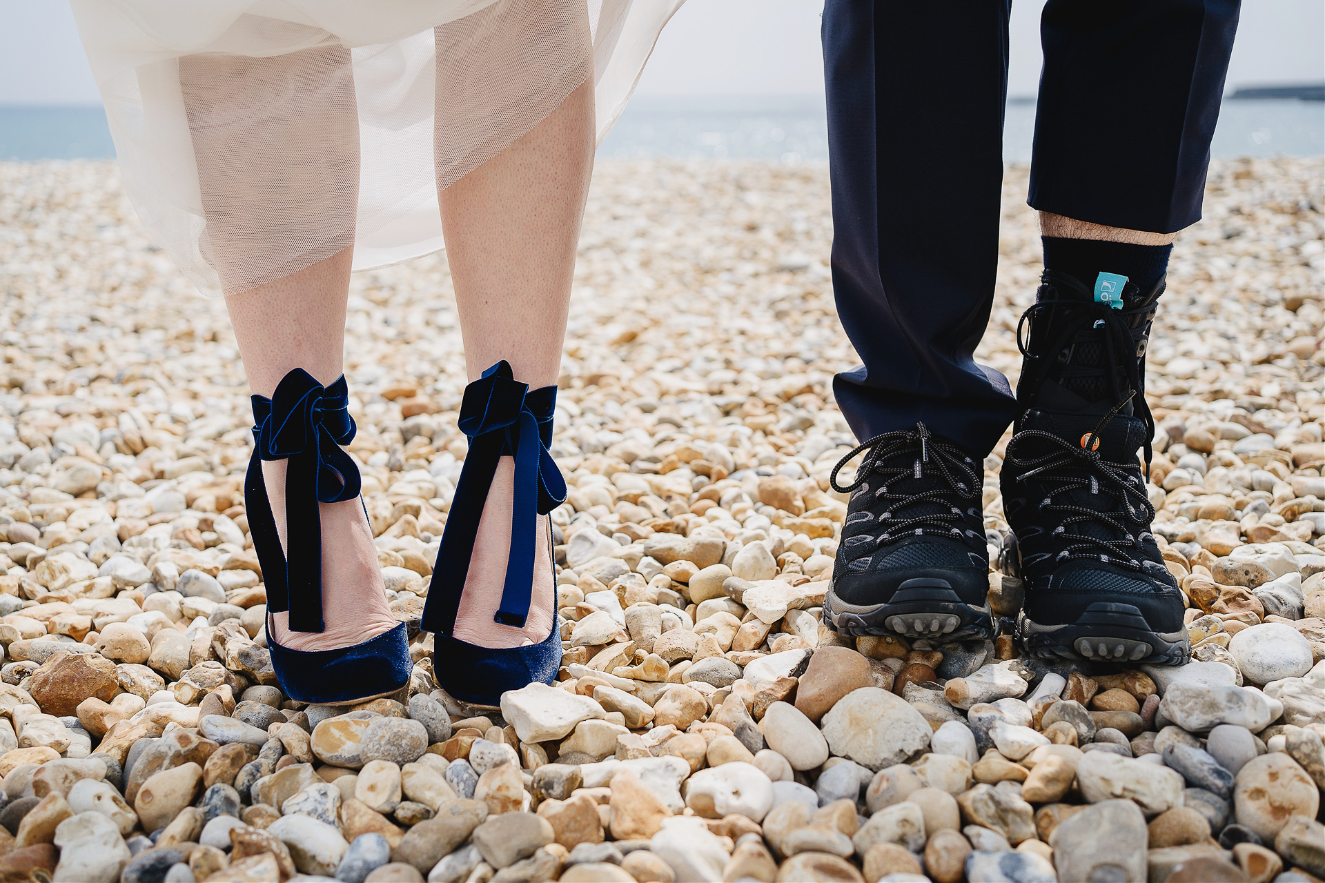Bride's feet with beautiful velvet blue shoes on a pebble beach