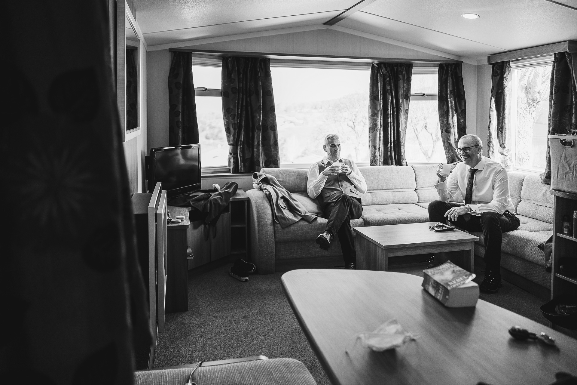 Groom and best man drinking tea in a caravan before elopement wedding