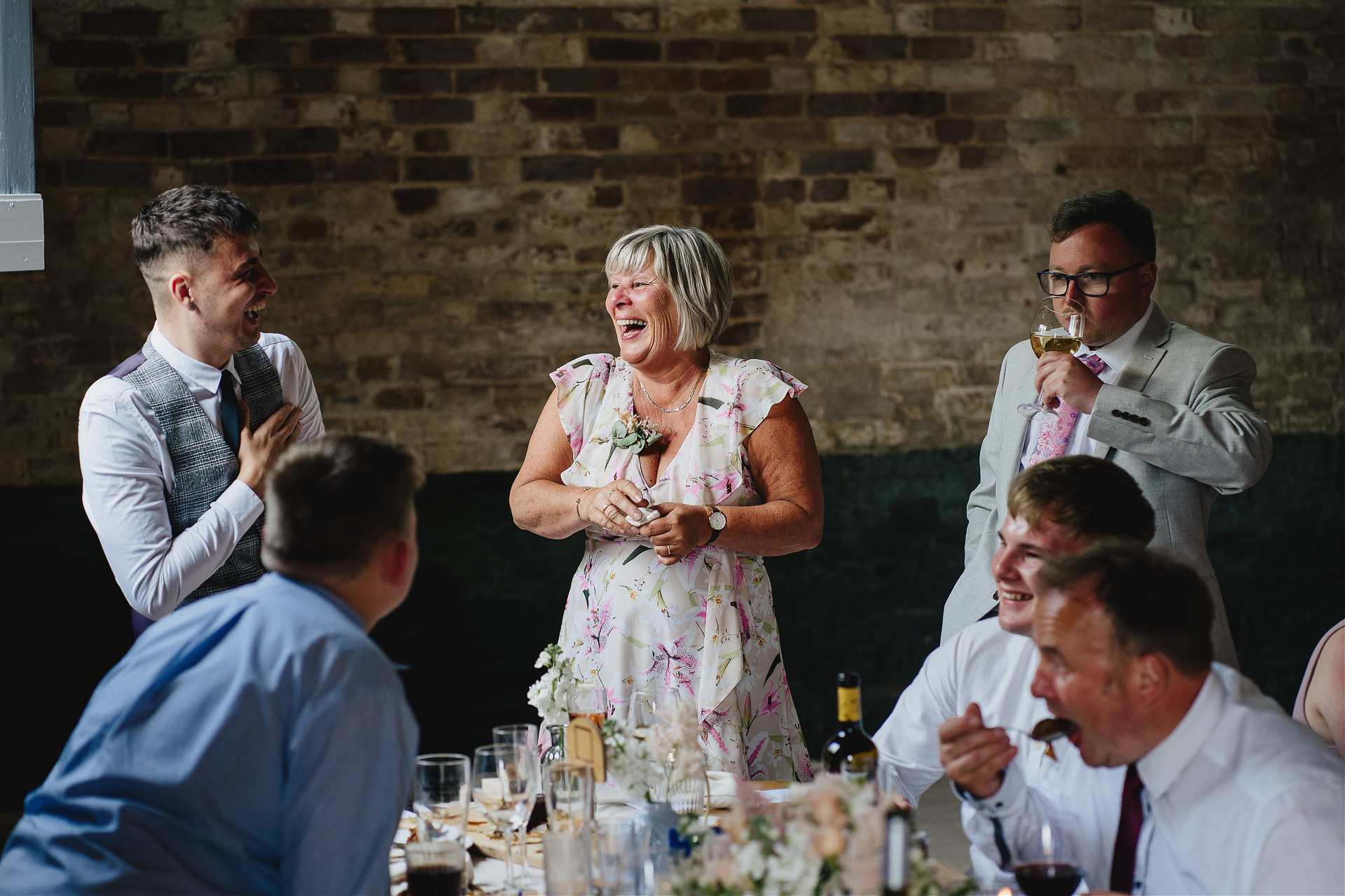 Wedding guests laughing and chatting inside a rustic barn