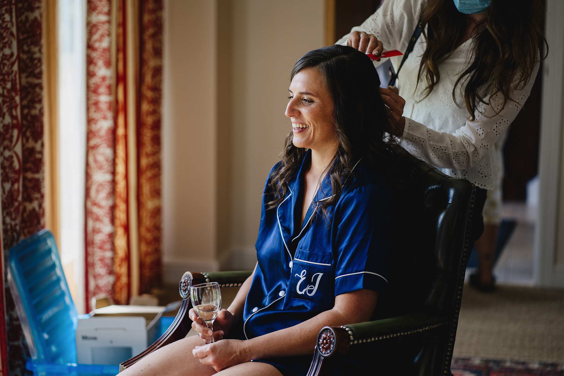Bride to be having her hair and make up done and smiling with a glass in hand