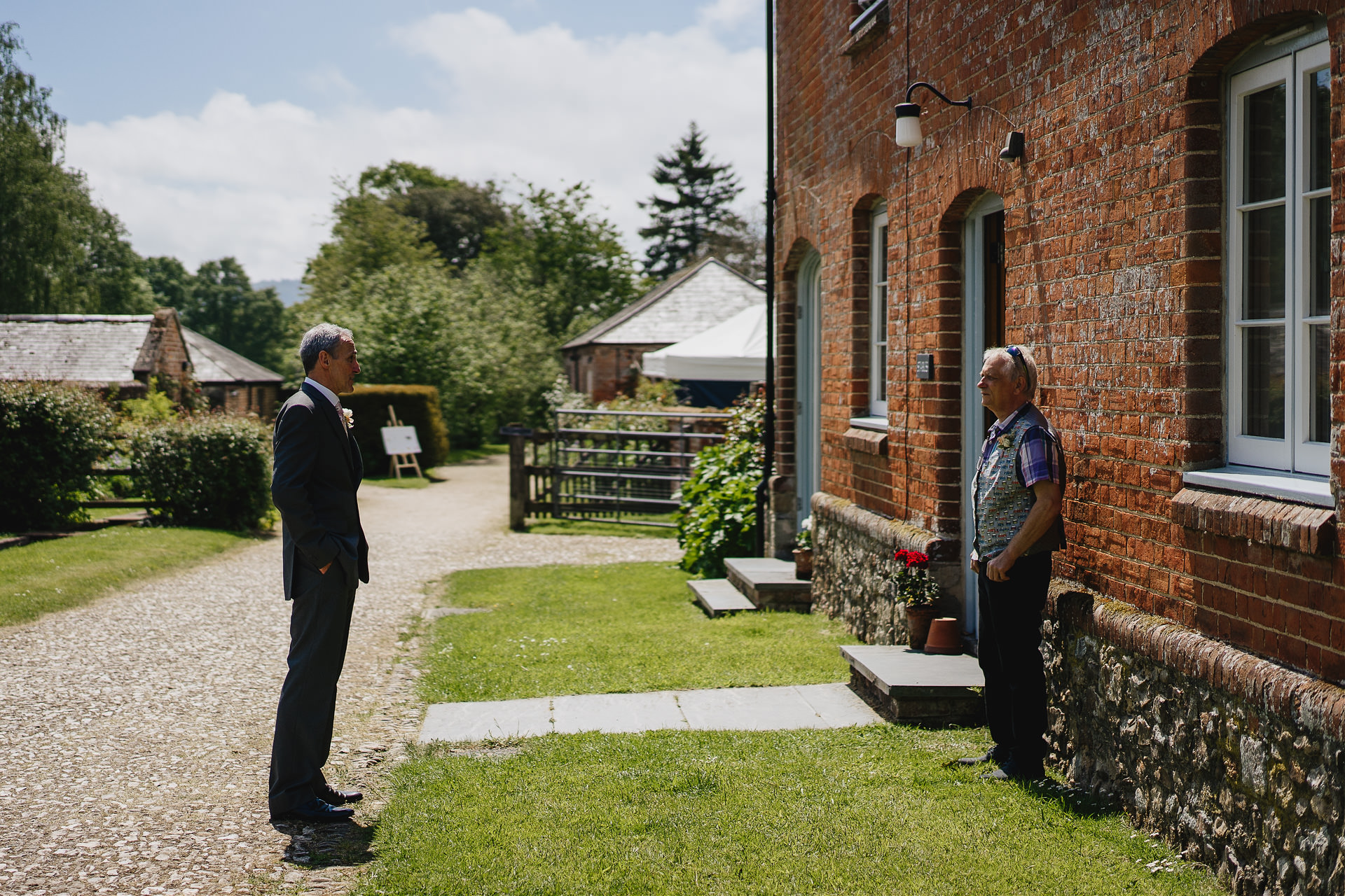Two fathers of brides talking to each other outside a rustic building