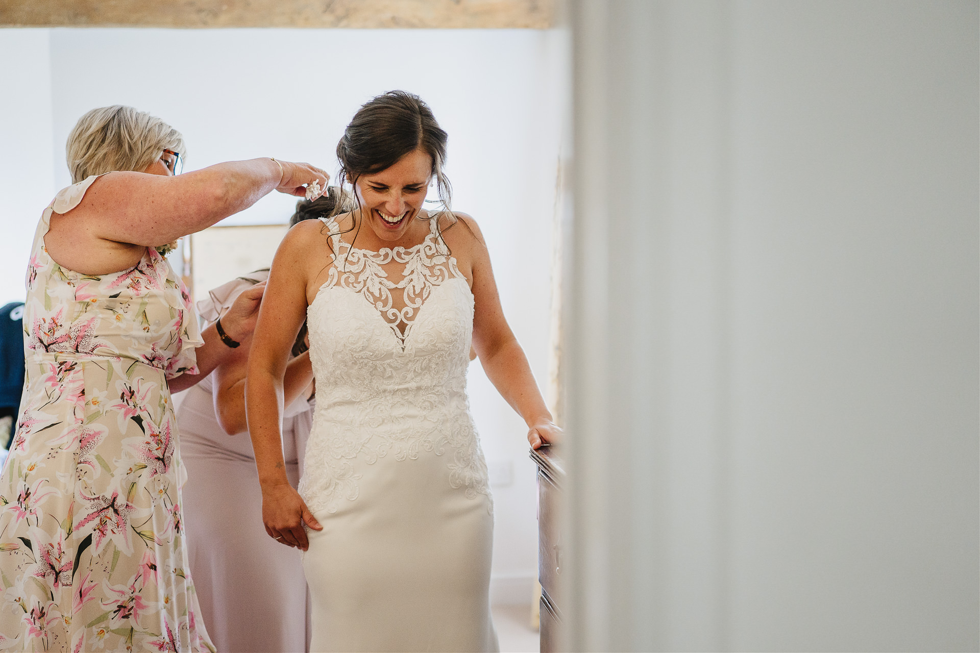 Bride to be putting on her wedding dress with family helping