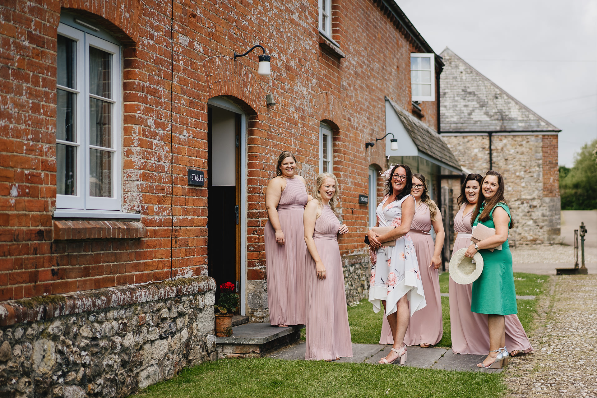 Bridesmaids and mother of the bride waiting outside a rustic building and smiling