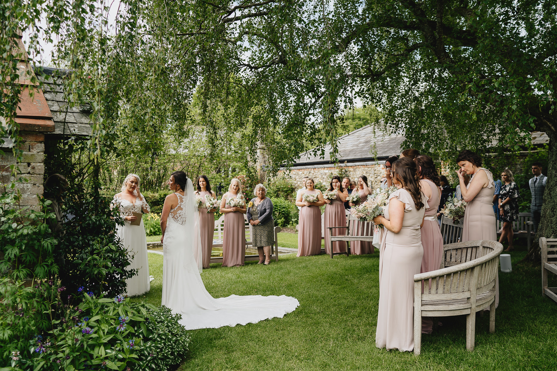 An outdoor ceremony during a Cadhay wedding with bride and bride under a birch tree. 