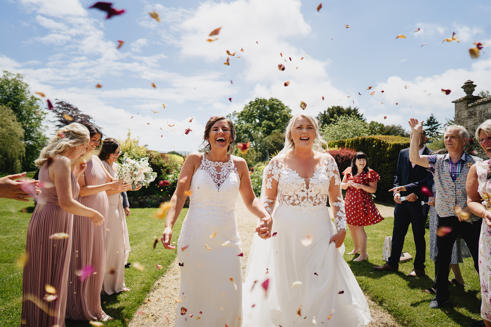 Bride and bride laughing as confetti is thrown over them