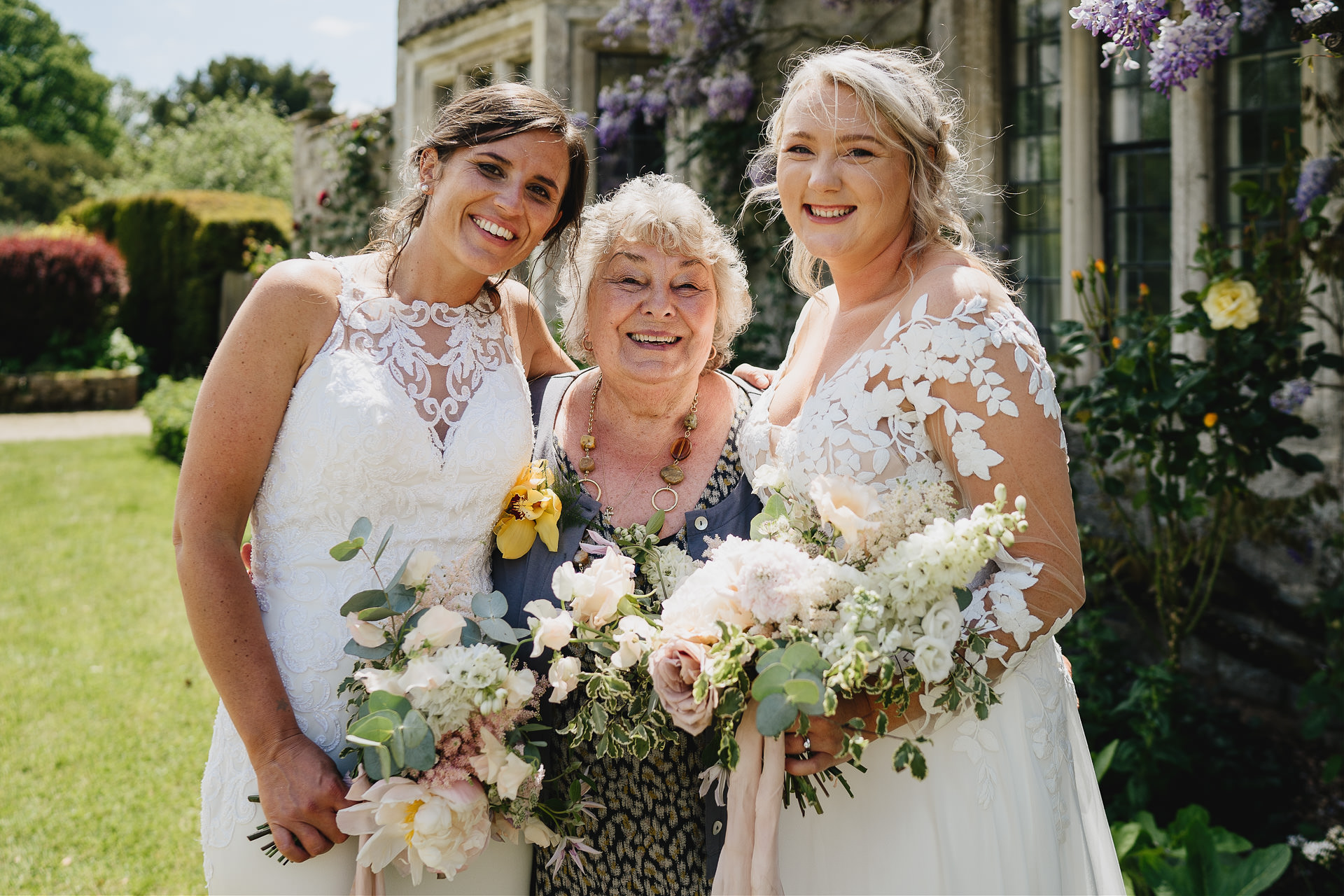 Two brides with a grandmother smiling at the camera