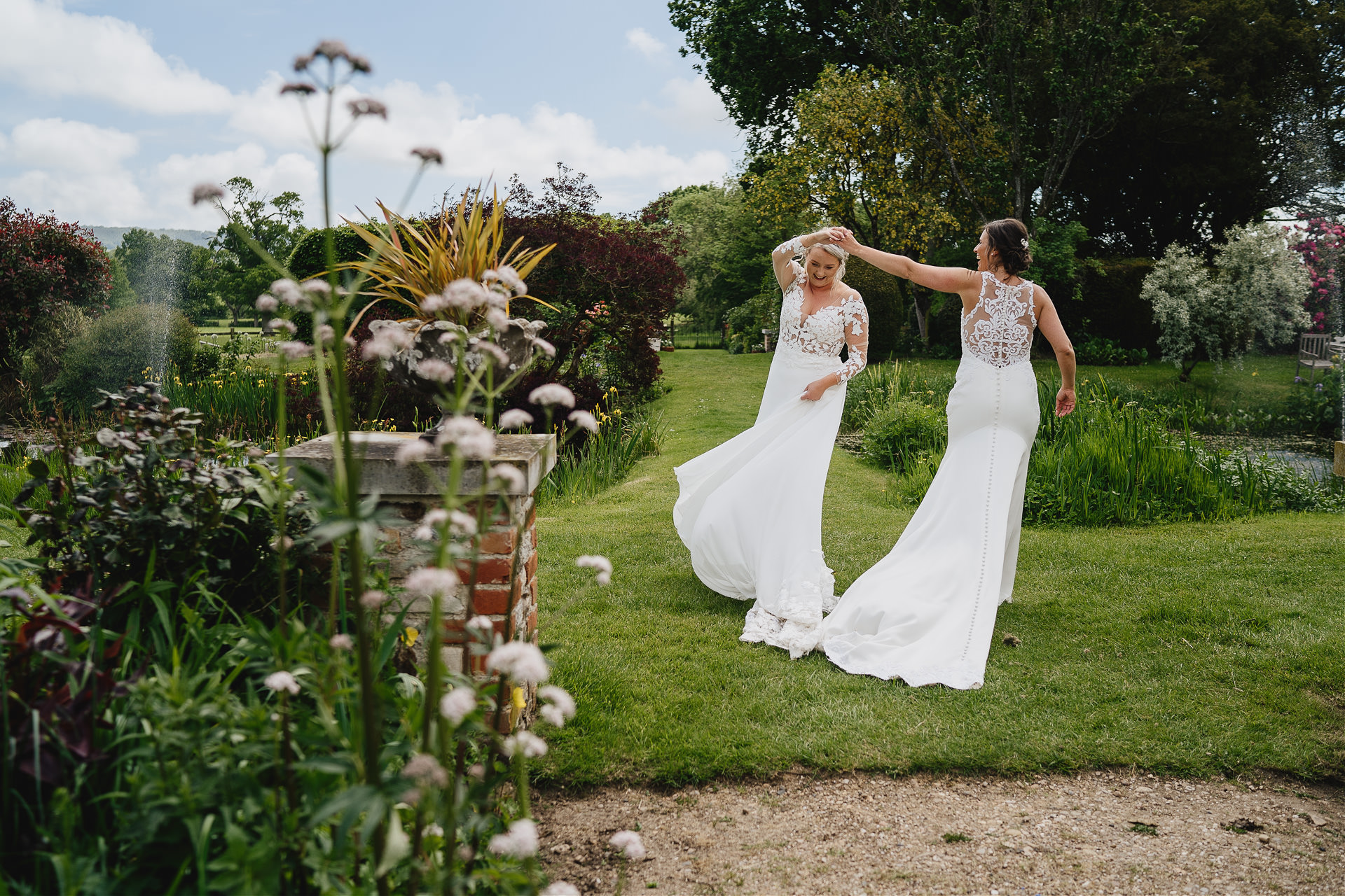 Two brides dancing in the gardens at Cadhay in Devon