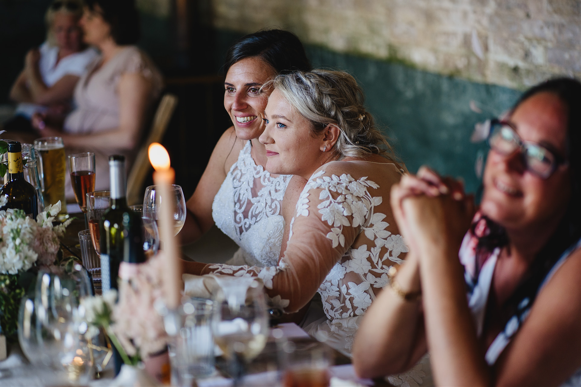 Two brides listening to wedding speeches and smiling together