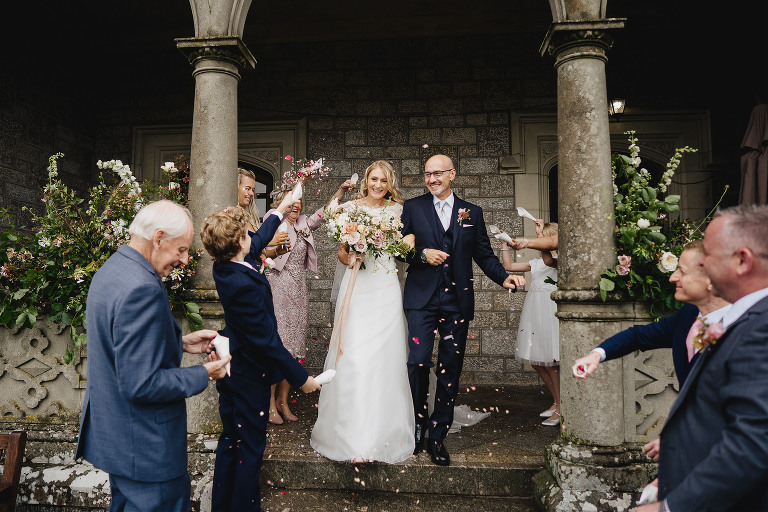 Bride and groom walking through confetti on the terrace at Bovey Castle