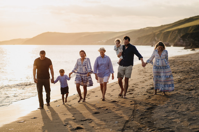 Family photography of a family group walking on the beach together at sunset