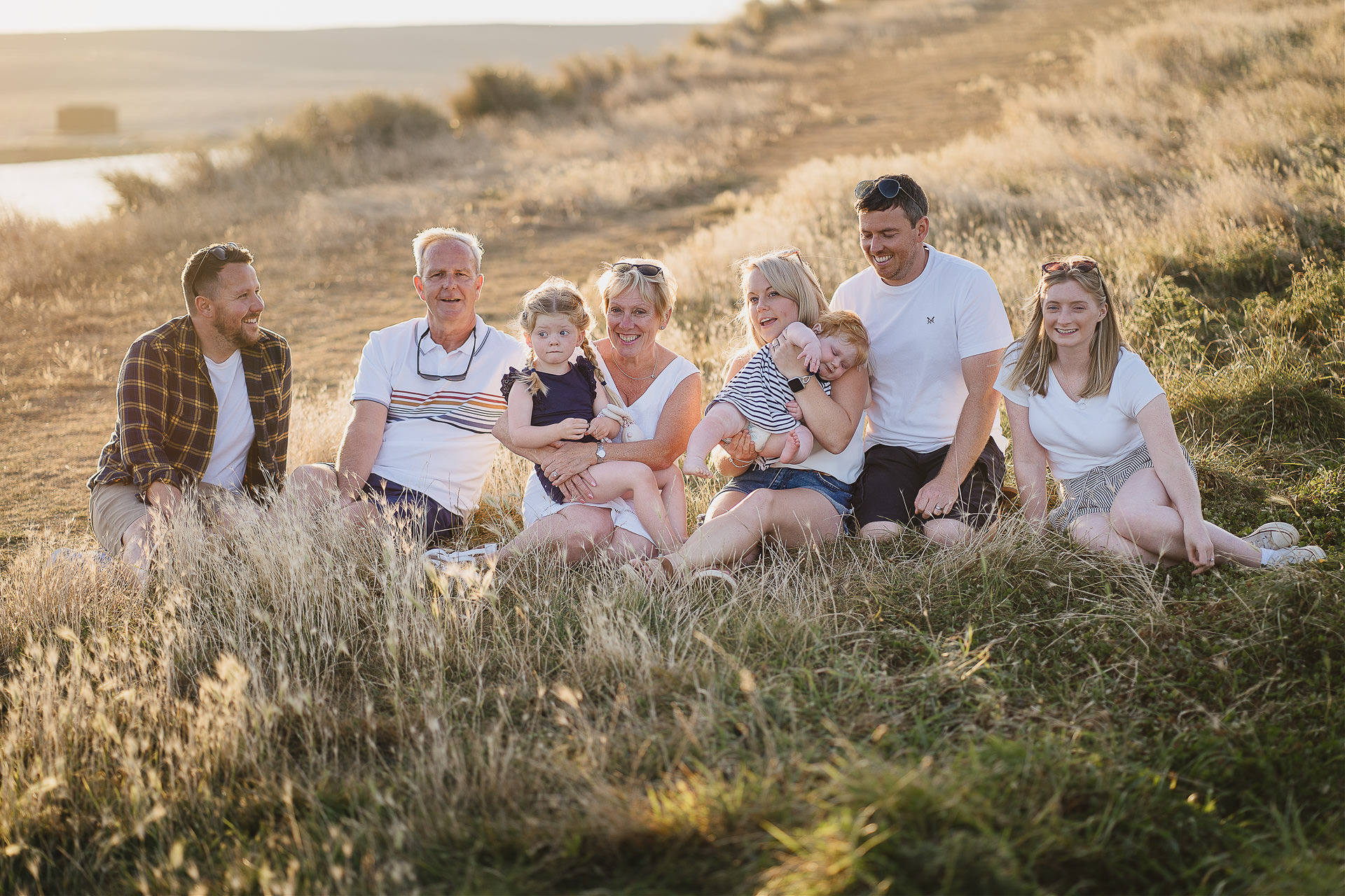 An extended family group photograph sitting in grass in a sunset