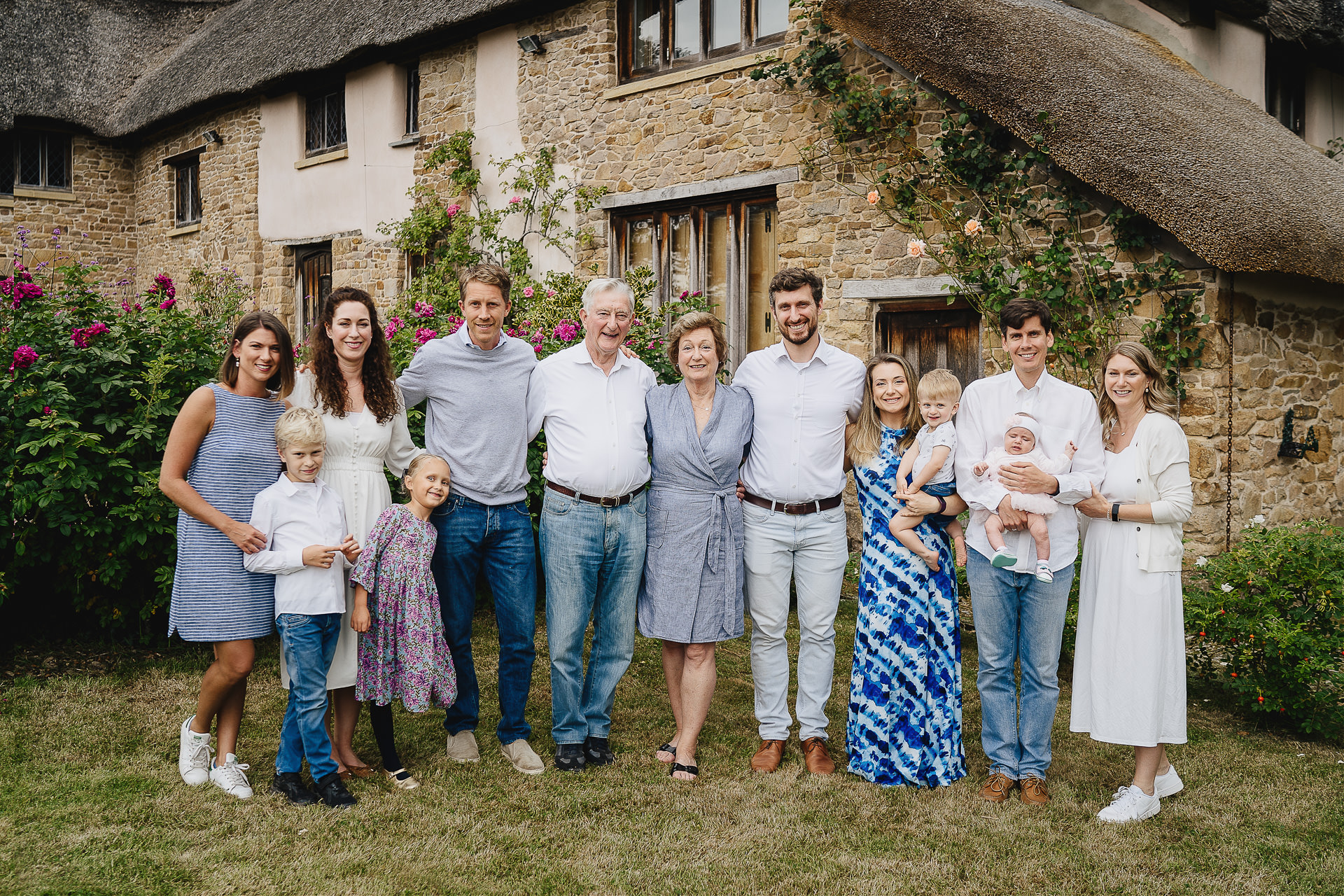 A large family photograph in front of a thatched cottage