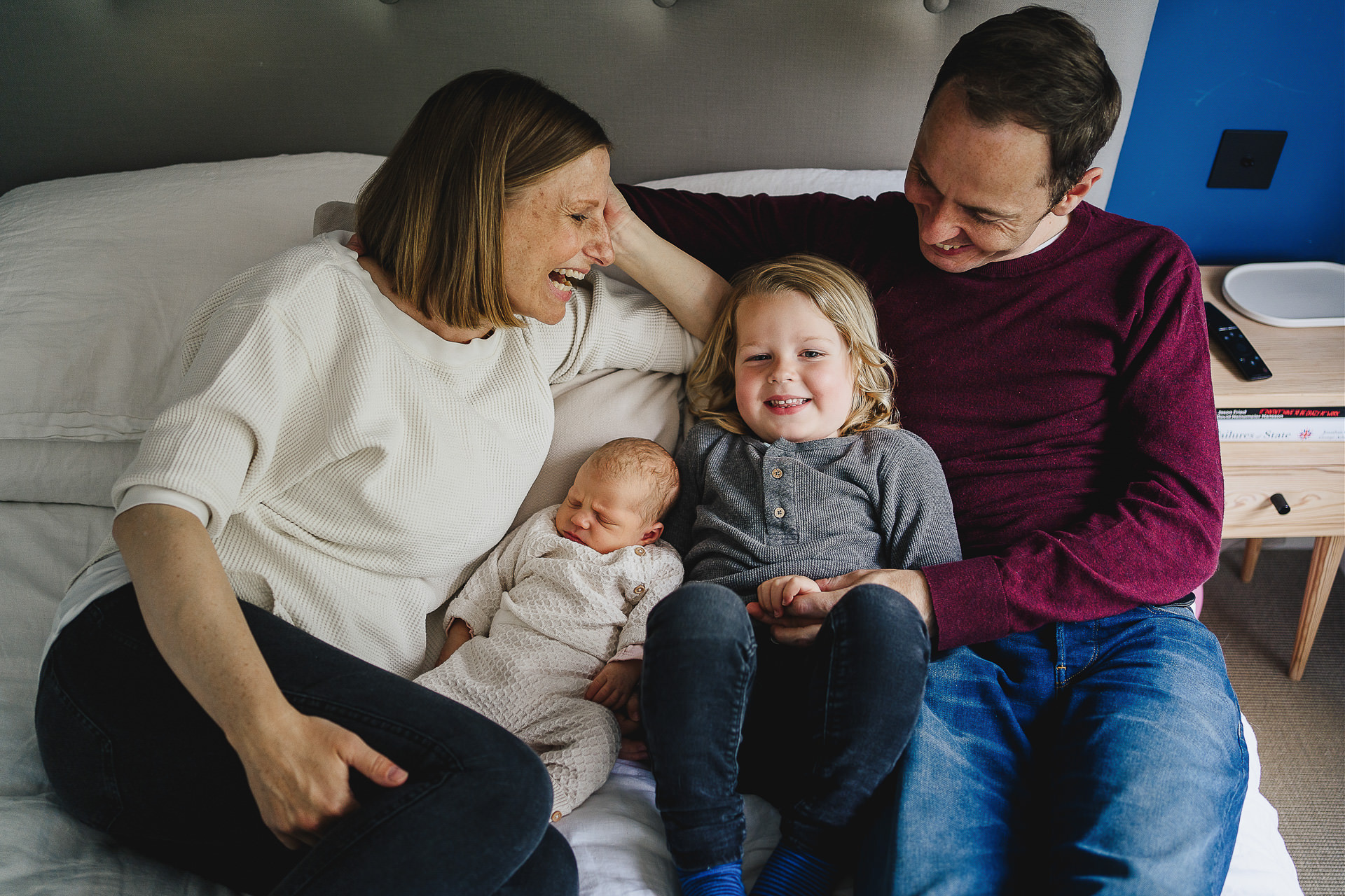 Family photography at home, with a family cuddling on a bed together