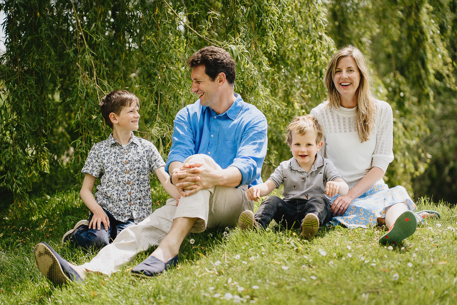 A relaxed family group photograph sitting on a grassy bank together