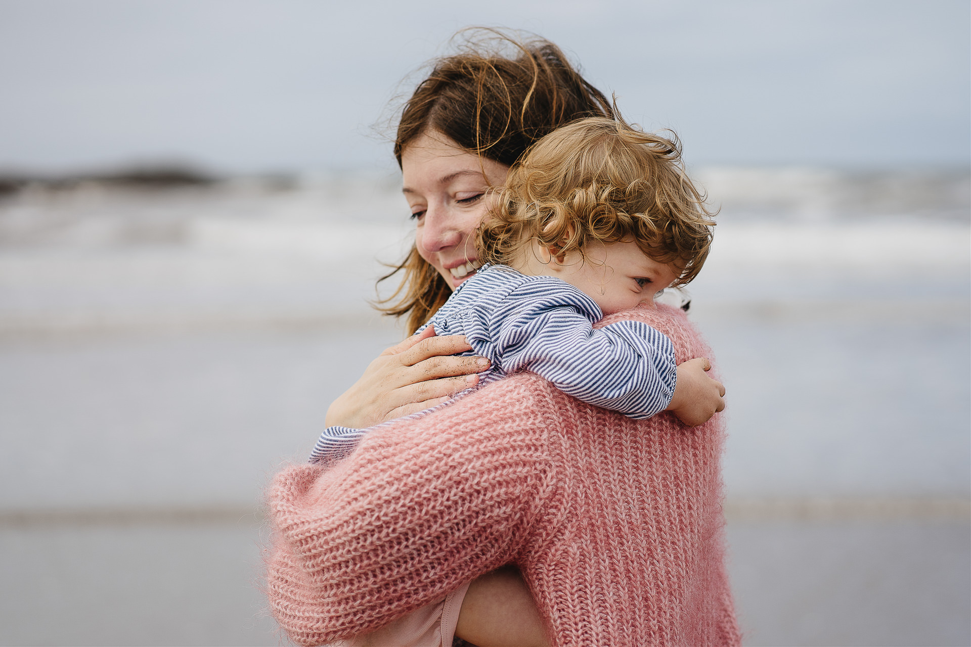 Mother cuddling a young girl on the beach during a family photography session