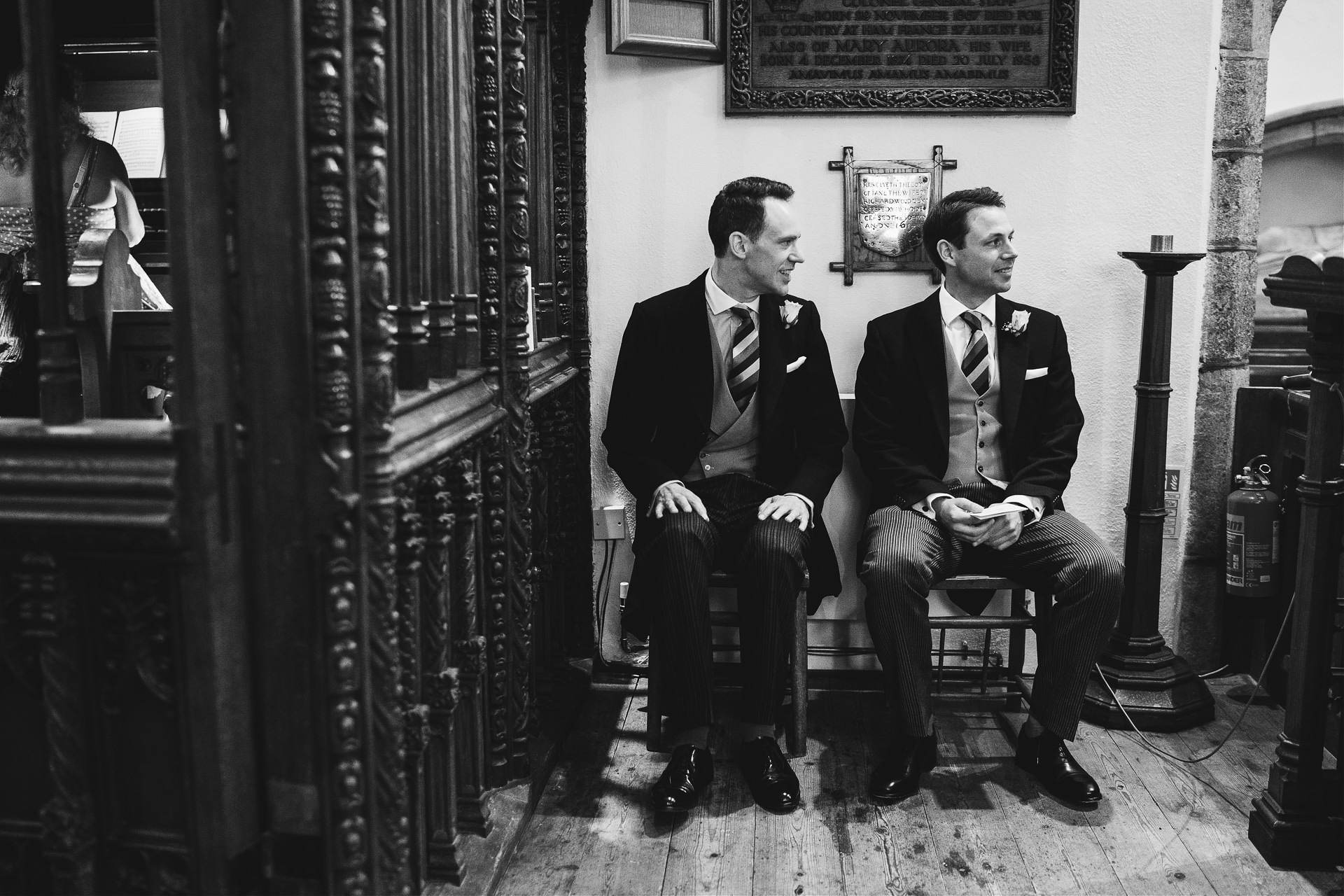 Groom and best man sitting side by side in a church